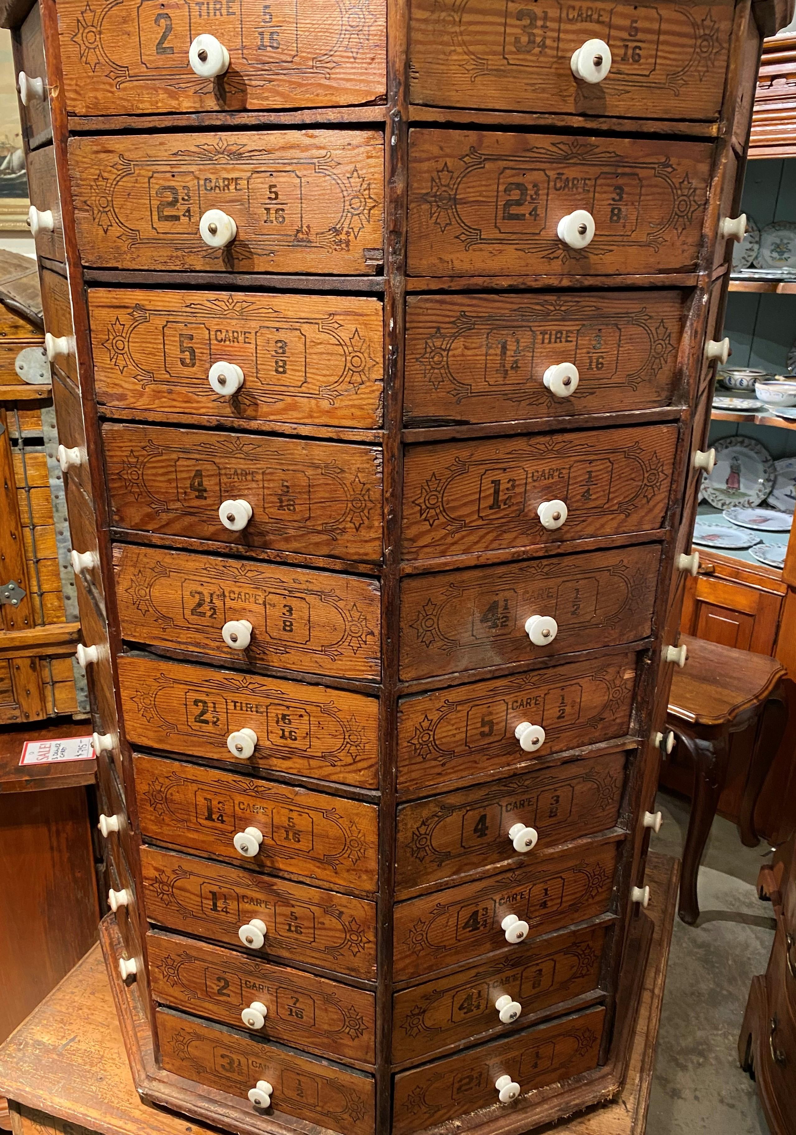 A wonderful large wooden hardware store revolving octagonal screw and bolt cabinet circa 1900 with 80 triangle fitted stenciled drawers in the upper revolving case, and an additional 17 drawers in the square base (7 drawers missing in the base). A
