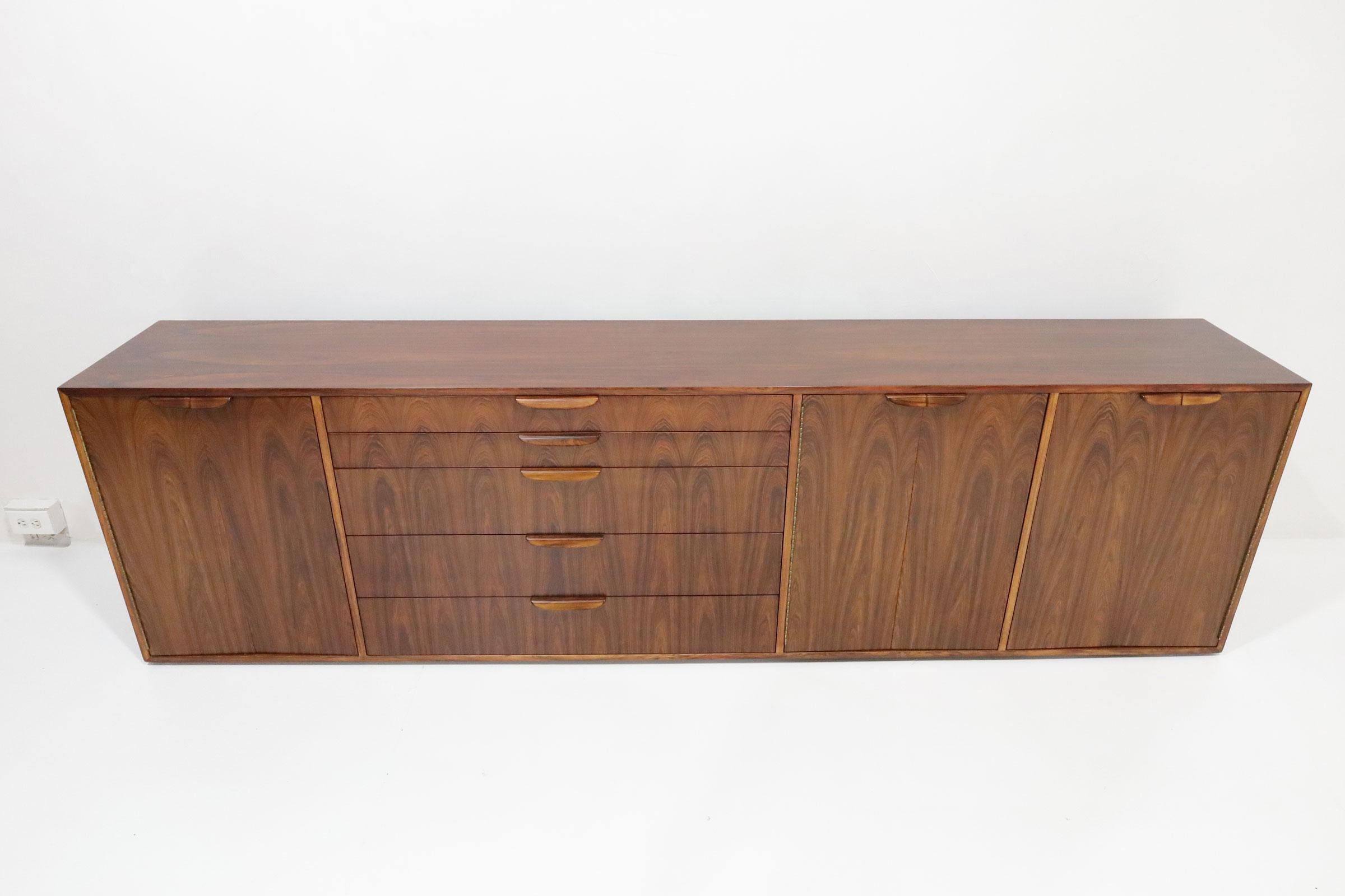 A spectacular large sideboard by Harvey Probber. This sideboard offers plenty of storage. The design is dramatic with a rosewood finish and book matched drawers. This is hard to find piece and will warm up any room with its rich wood grain. Interior