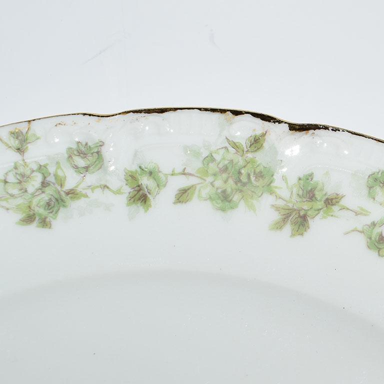 Porcelain set of signed Limoges Haviland France tableware. Each piece is in a crisp white porcelain. Green foliage and hand painted gold decorates the edges. Some pieces such as the cups feature a satsuma style texture protruding from the lips and