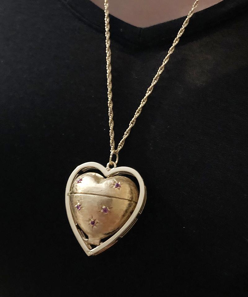 Large and fabulous figural puffy heart locket.  The heart is suspended within a triple shiny gold border.  One side of the heart is set with faceted sapphires; the other side, with bright faceted rubies.  The heart pushes out from the frame and