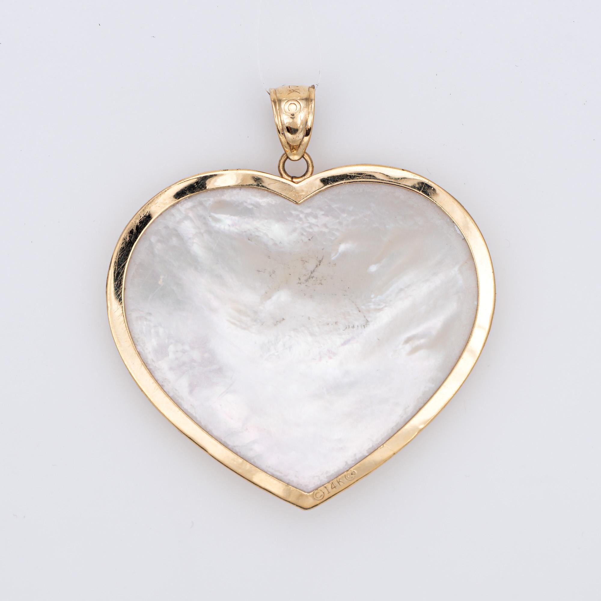 Finely detailed estate large heart pendant crafted in 14k yellow gold.

Mother of pearl measures 32mm x 28mm (in very good condition and free of cracks or chips).  

The distinct and beautifully detailed pendant features a scrolled design over