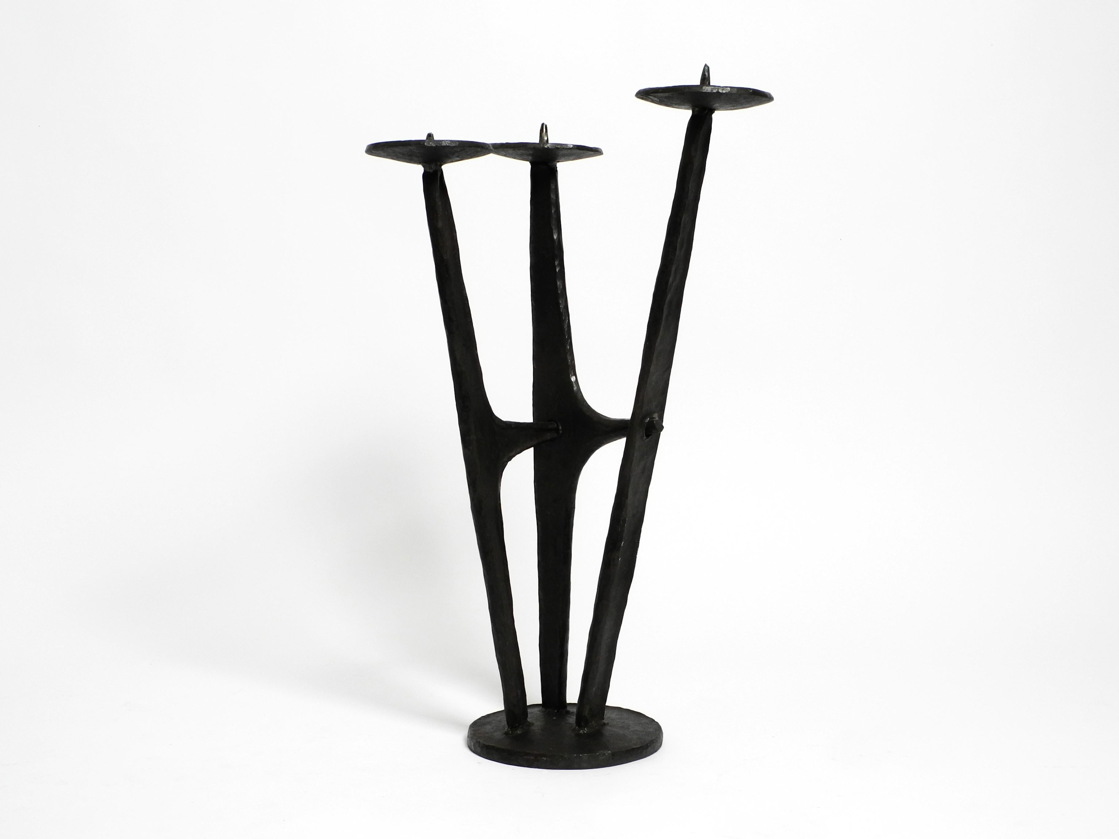 Extraordinary large, heavy 1950s floor candlestick made of wrought iron in a typical Mid Century Streamline design. Beautiful rare decoration for all living areas.
The heavy design piece wit a height of  65cm without candles and a weight of approx.