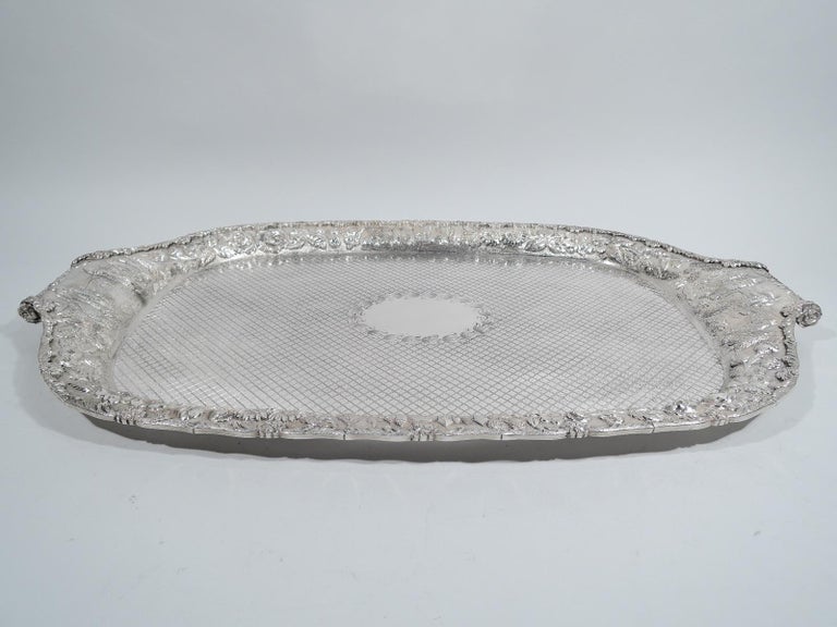 Large & heavy American sterling silver tea tray, ca 1890. Well has engraved flower-head frame (vacant) surrounded by allover flower-inset diaper. Wide shoulder with repousse floral garland, and picturesque turrets and bridges. A great