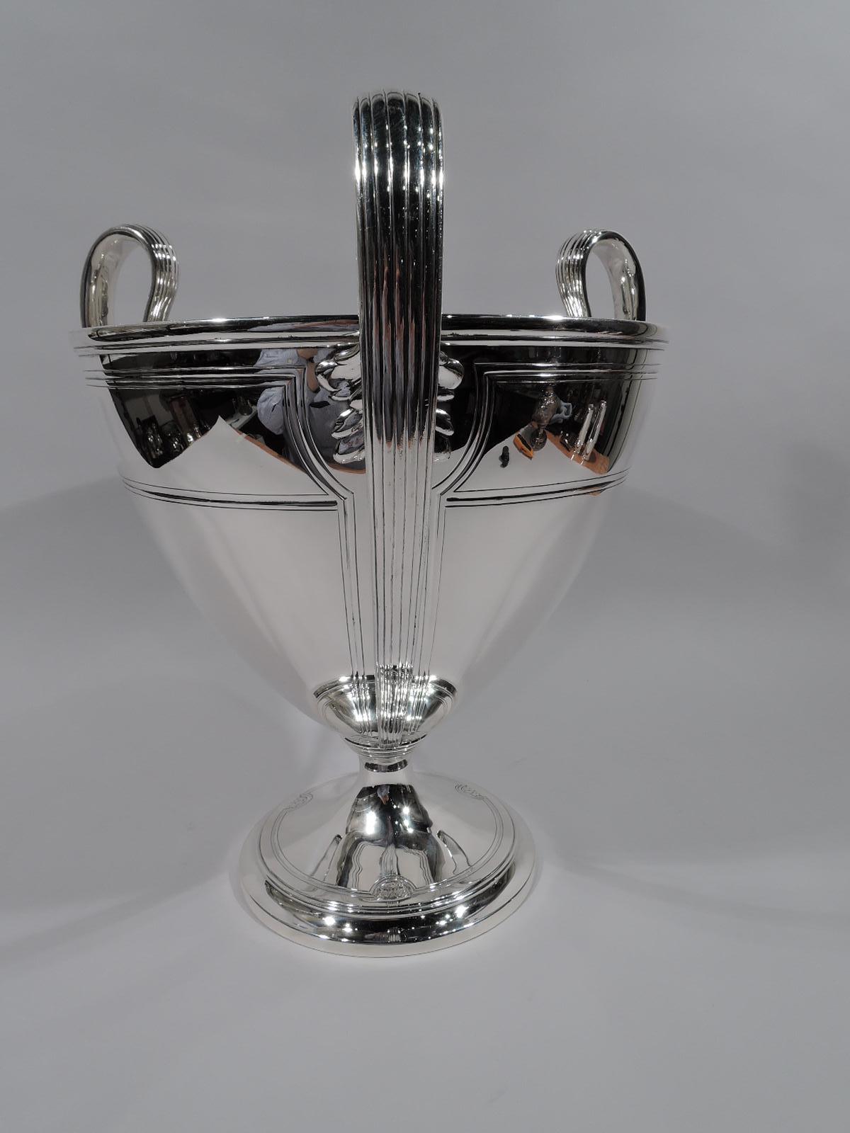Large and heavy Art Deco Classical sterling silver trophy cup. Made by Tiffany & Co. in New York, circa 1912. Ovoid bowl on stepped foot. Three high-looping and reeded tapering leaf-mounted handles. On exterior are 3 chased paneled curvilinear