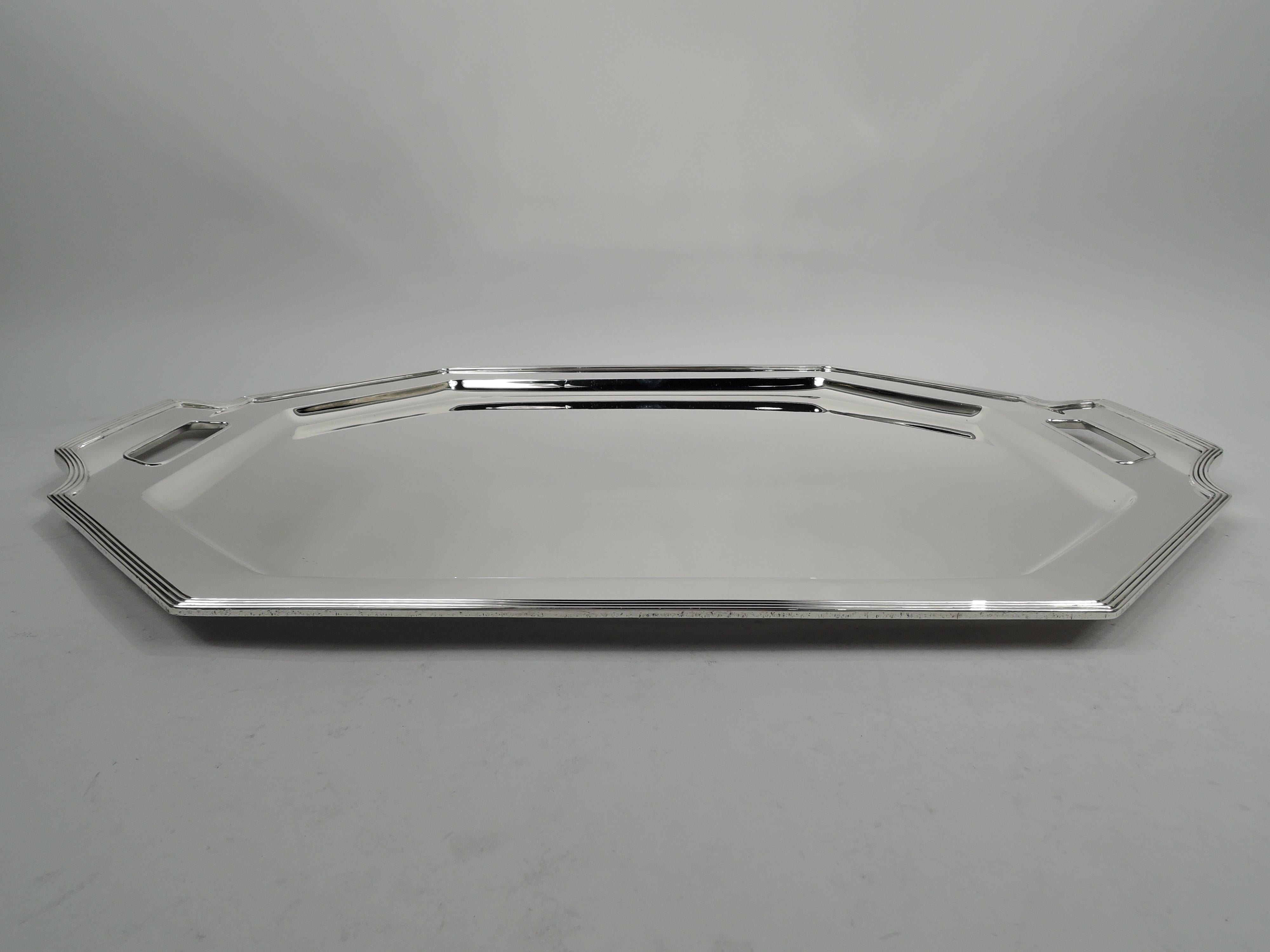 Large and heavy Art Deco sterling silver tea tray. Made by Tiffany & Co. in New York, circa 1916. Rectangular well with chamfered corners, wide shoulder, and reeded rim; curvilinear ends with cutout trapezoidal handles. A striking design that would