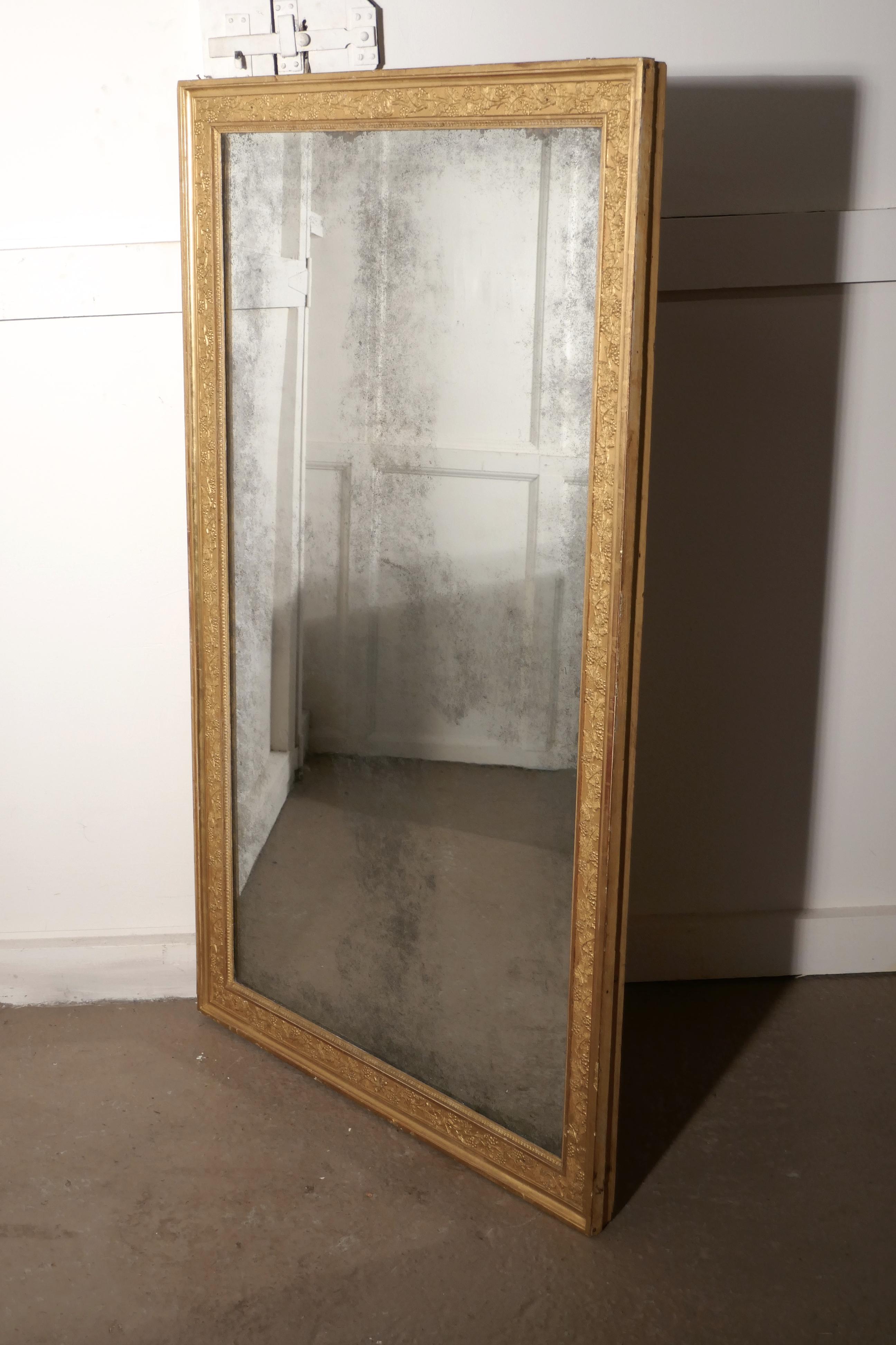 Large heavy French gold shabby wall mirror.

This is a charming piece of shabby elegance, the aged gold mirror frame is 3” wide and carved with grapes and vines carved all the way around with the exception of one little bit at the top where we can