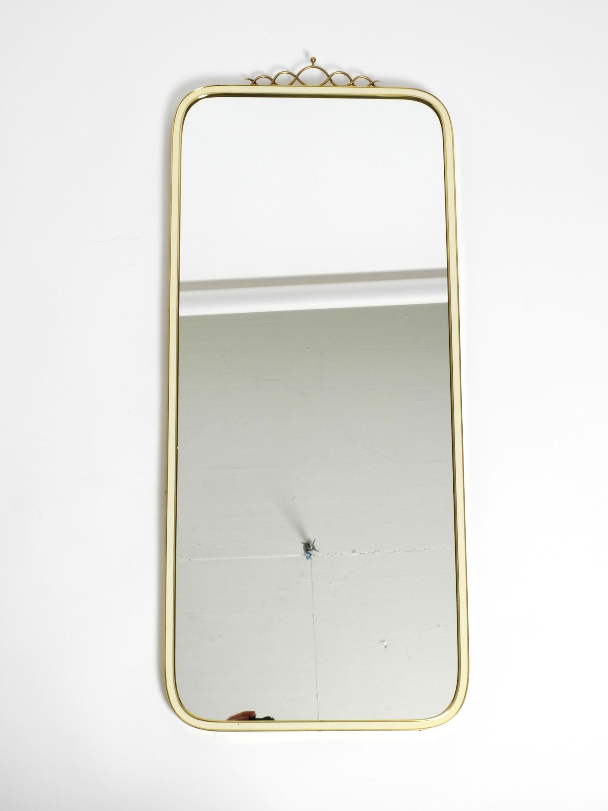 Large, long and heavy Mid Century brass wall mirror.
Manufacturer is Münchner Zierspiegel, Made in Germany.
Great minimalist design. With screwed brass crown on top. In fantastically good condition.
Frame is made entirely of solid brass, partly