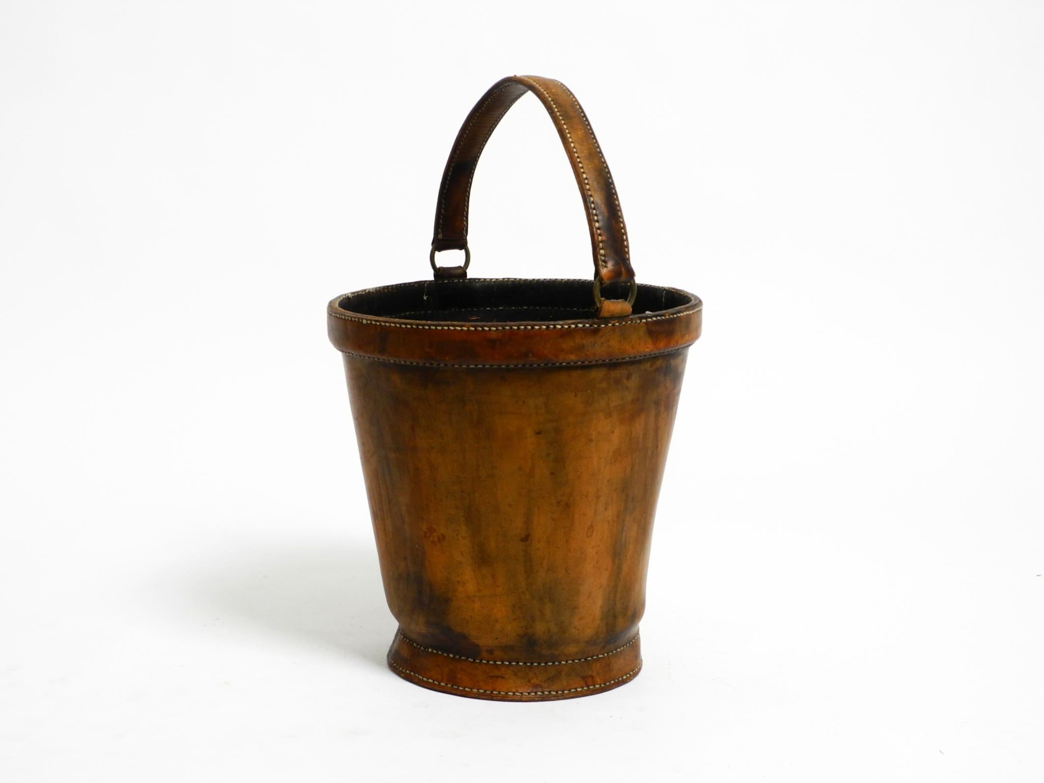 Large, heavy mid-century modern wastepaper basket made of sturdy, thick brown cowhide.
Can also be used for other purposes.
Very stable and sturdy thanks to the thick leather. Well-greased. Black interior.
No damage, no cracks, or deformation. All