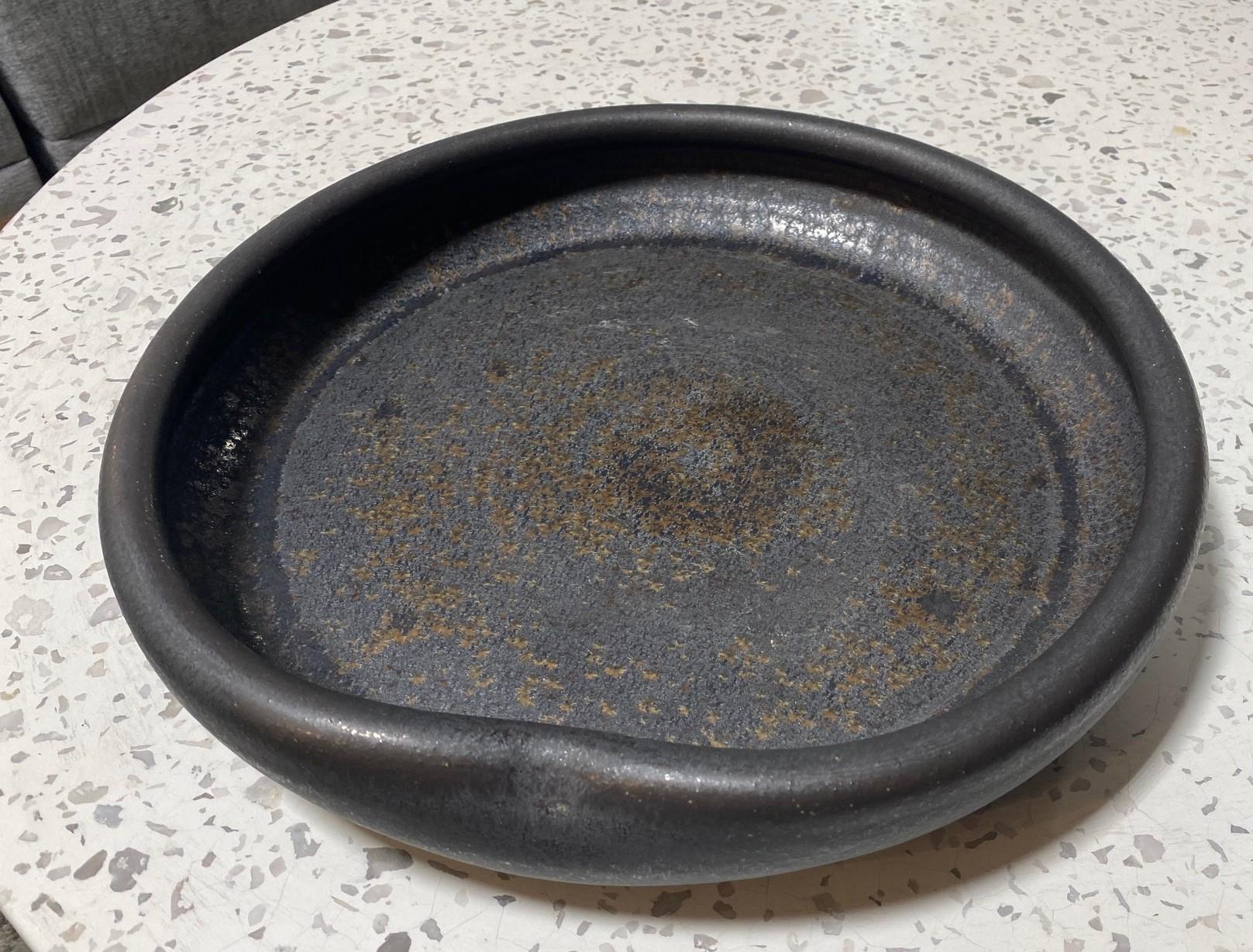 A truly fabulous, large, heavy, wonderfully crafted, and uniquely designed centerpiece Studio Pottery bowl. The work features a fantastic black metallic glaze similar to works by Otto and Gertrude Natzler. Quite spectacular. 

Signed by the