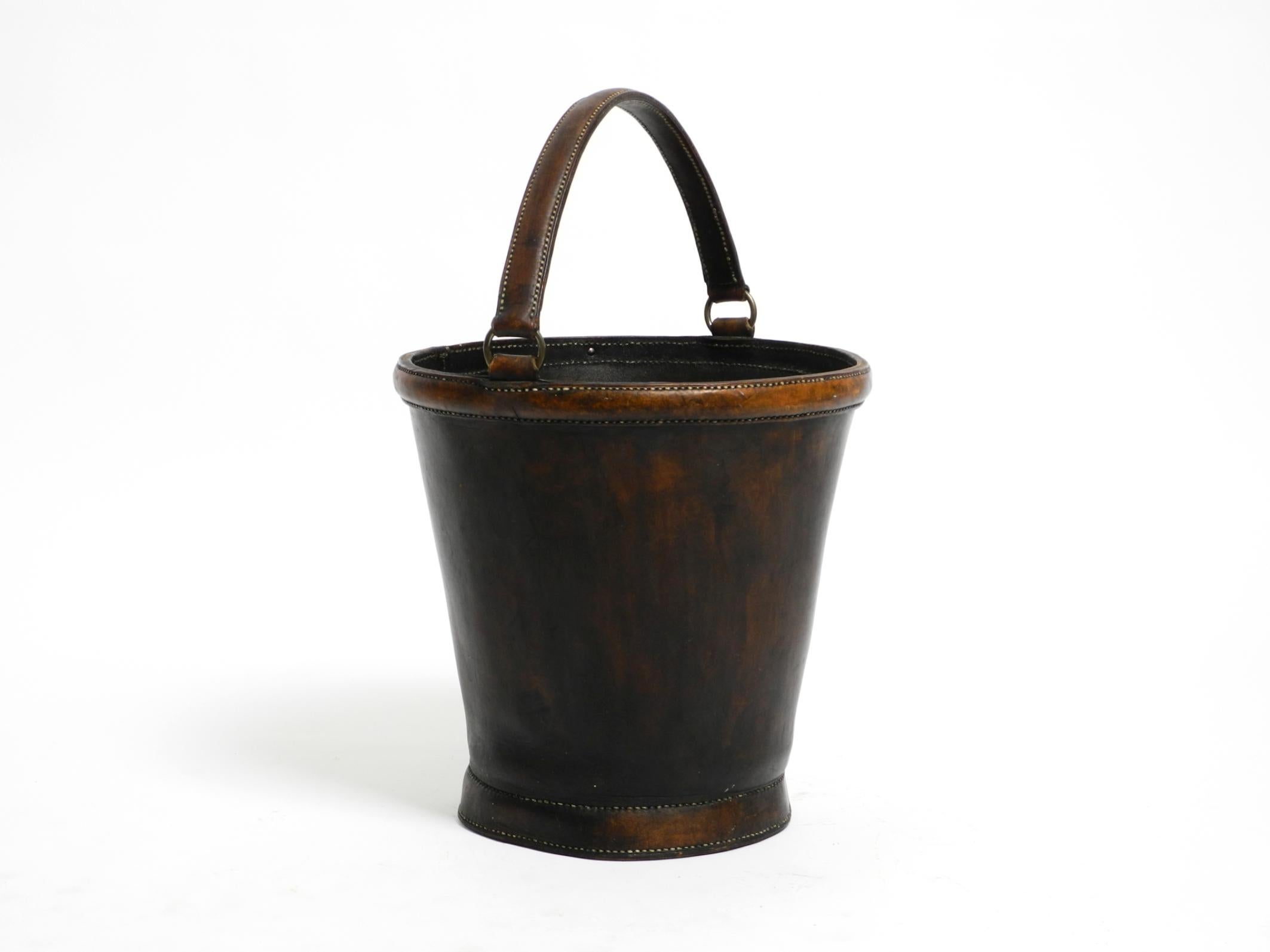 Large, heavy mid-century modern wastepaper basket made of robust, thick, dark brown cowhide.
Can also be used for other purposes.
Very sturdy and durable thanks to the thick leather. Well-greased. Black interior.
No damage, no cracks, or