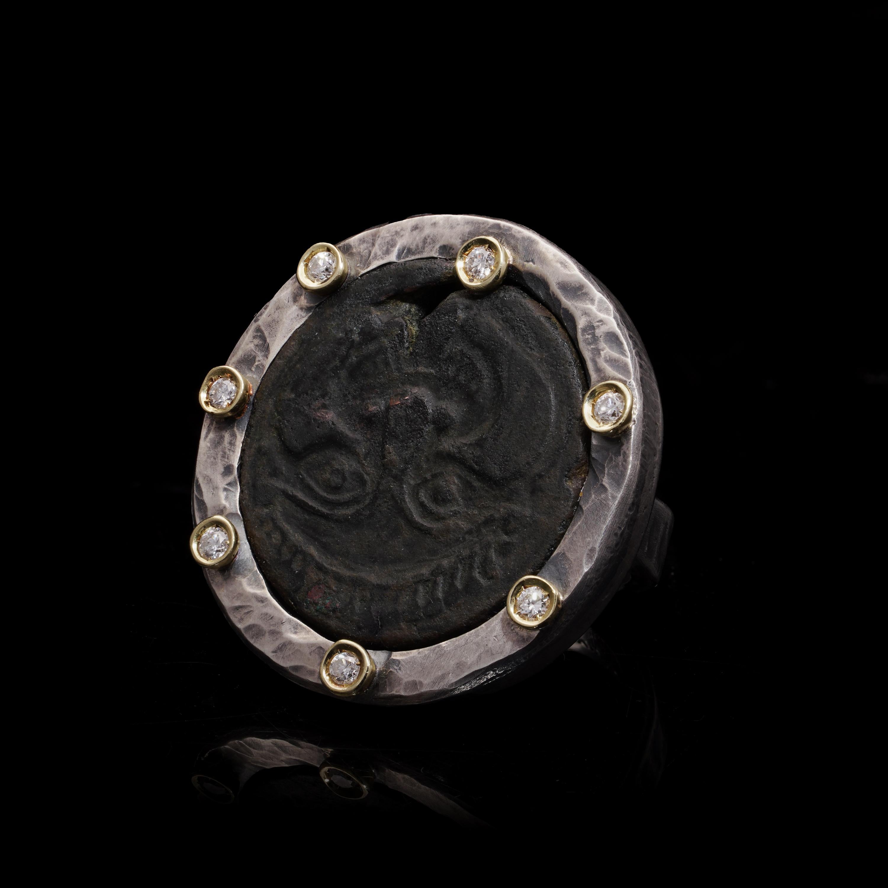 Kiai Grande bague en argent lourd avec pièce de monnaie ancienne

Cette bague étonnante présente une pièce de monnaie ancienne sertie dans un anneau d'argent martelé, orné de touches d'or 18kt sur le pourtour. La pièce est identifiée comme une pièce