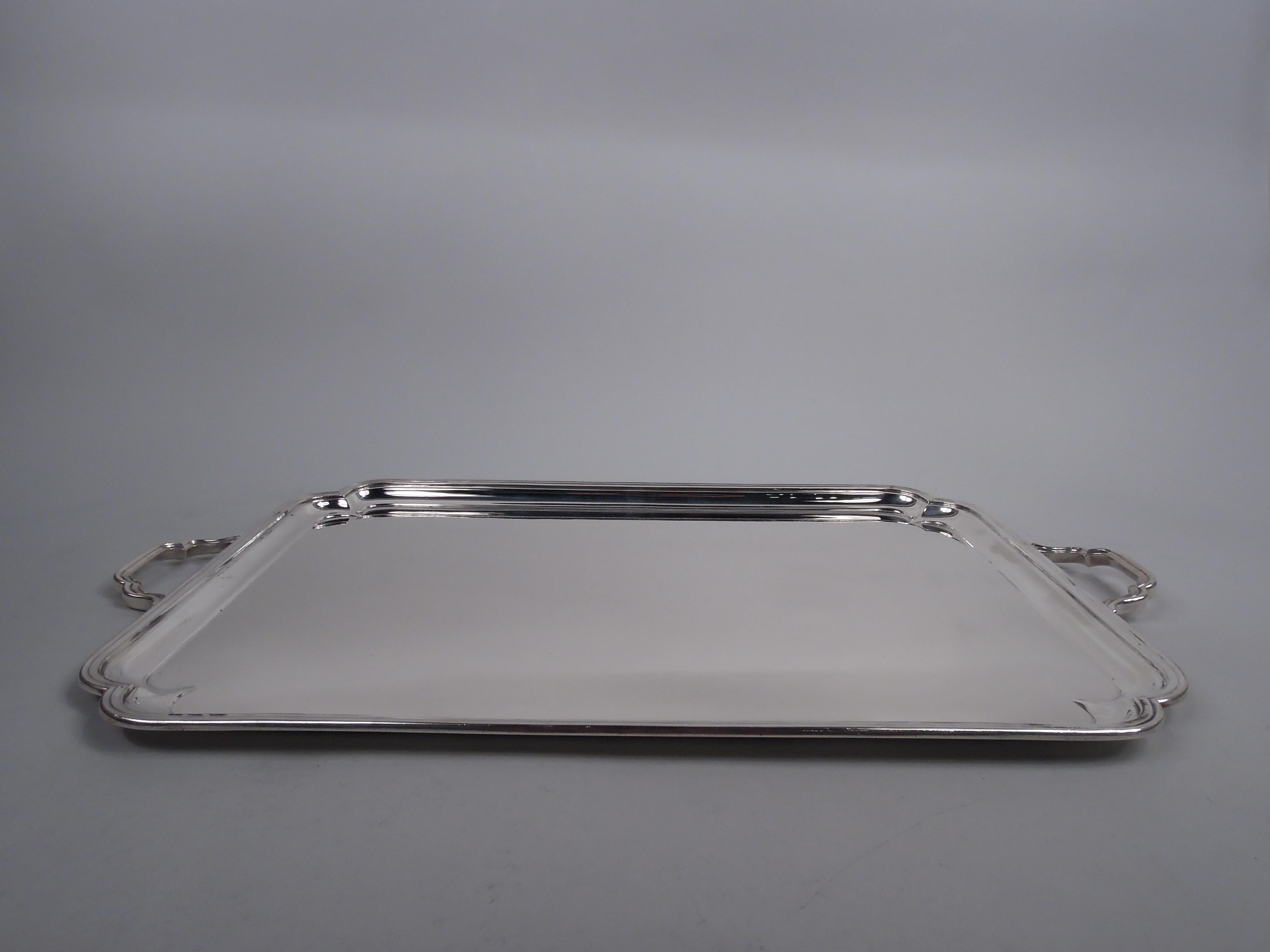 George VI sterling silver tray. Made by Thomas Bradbury & Sons Ltd in Sheffield in 1946. Rectangular with molded rim and double-scroll corners; end bracket handles same. Traditional Georgian for the postwar era. Fully marked including retailer’s