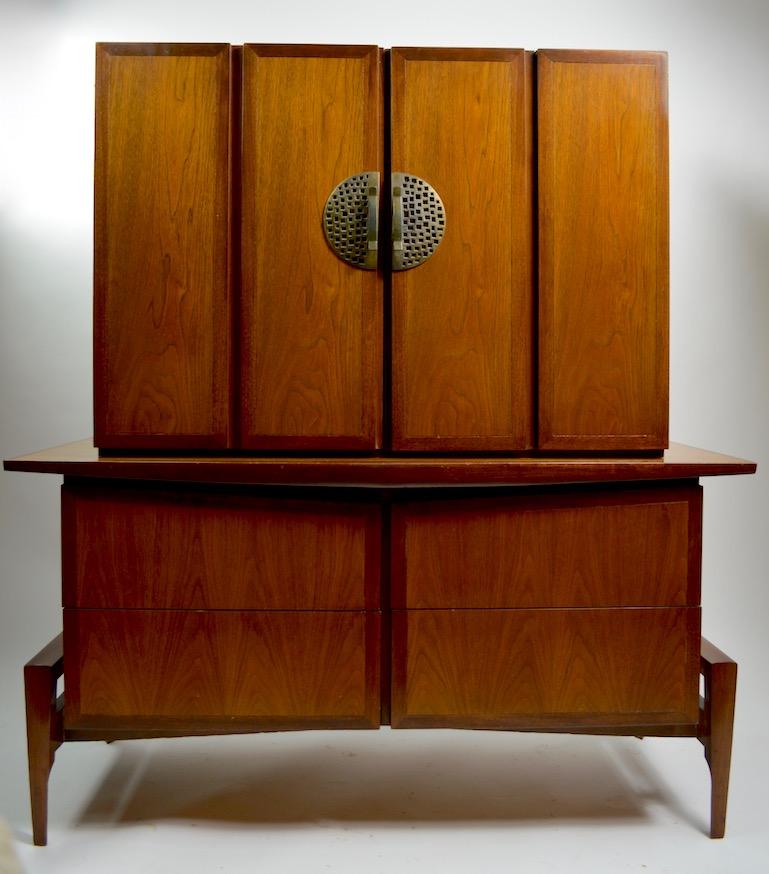 Classic midcentury Gentleman's chest by Helen Hobey, for Baker. This chest on chest has a top cabinet which has two swing out doors that open to revel four interior drawers, above a four drawer base. The dresser has ample storage space, it is well
