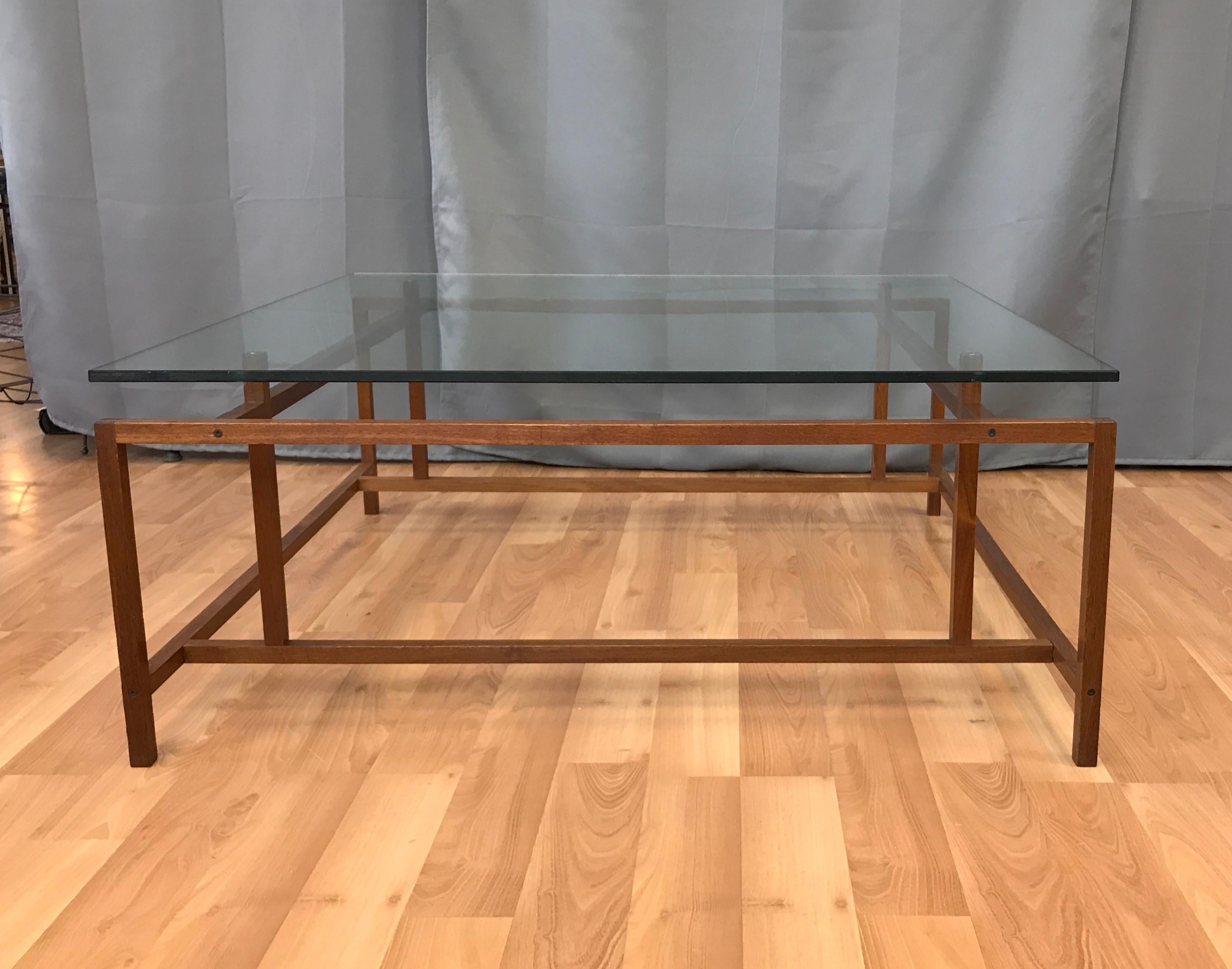 An architectural teak coffee/cocktail table with glass top by Henning Nørgaard for Komfort. 

Minimalist geometric solid teak base displays excellent craftsmanship, with both mortise-and-Tenon and finger joinery. Has original glass top.