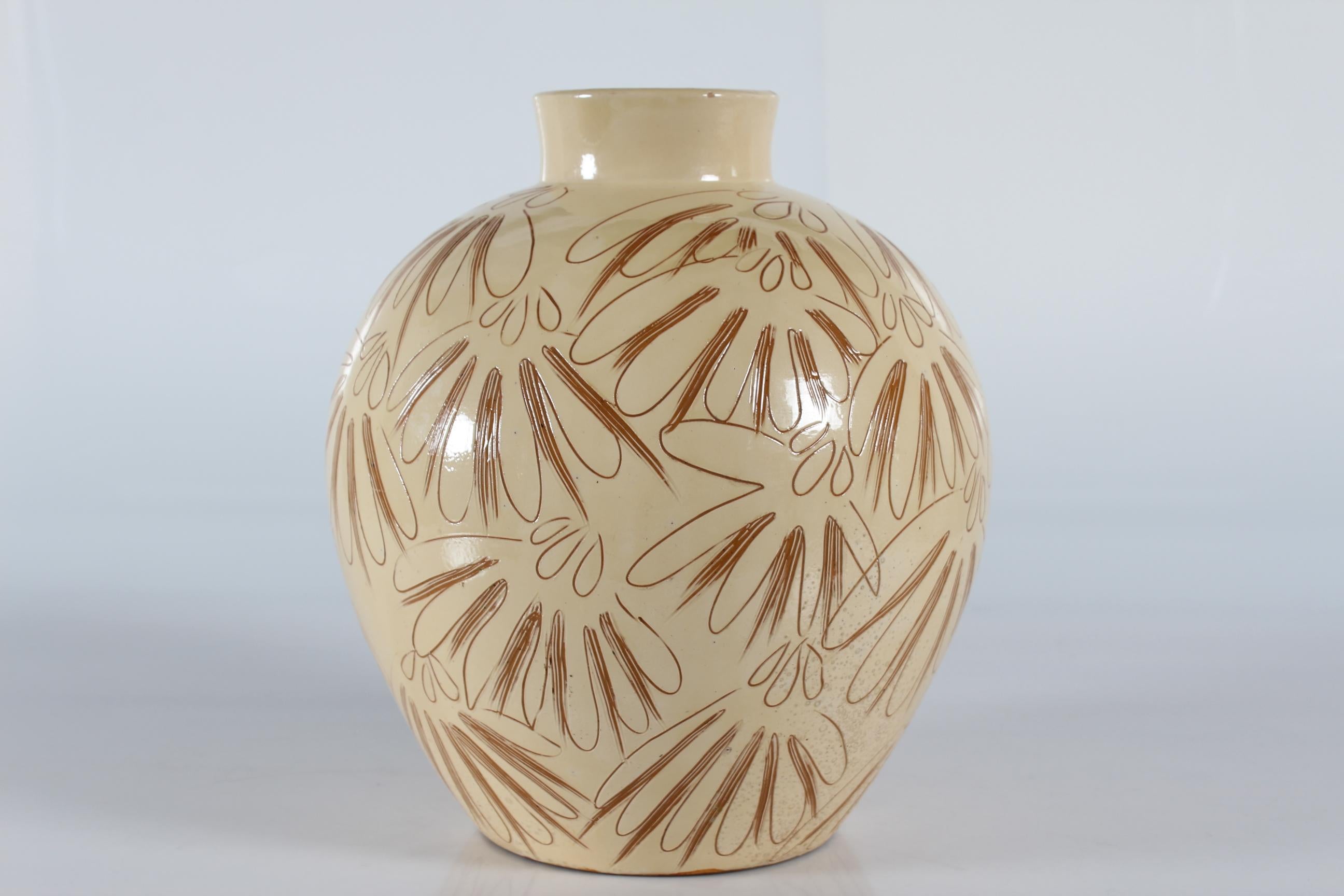 Énorme vase de sol danois en céramique réalisé par Herman A. Kähler dans les années 1940-50.
Le vase de sol a une base jaune crème avec une décoration incisée où la couleur de l'argile brune apparaît. La technique est appelée Sgraffito.
Cette