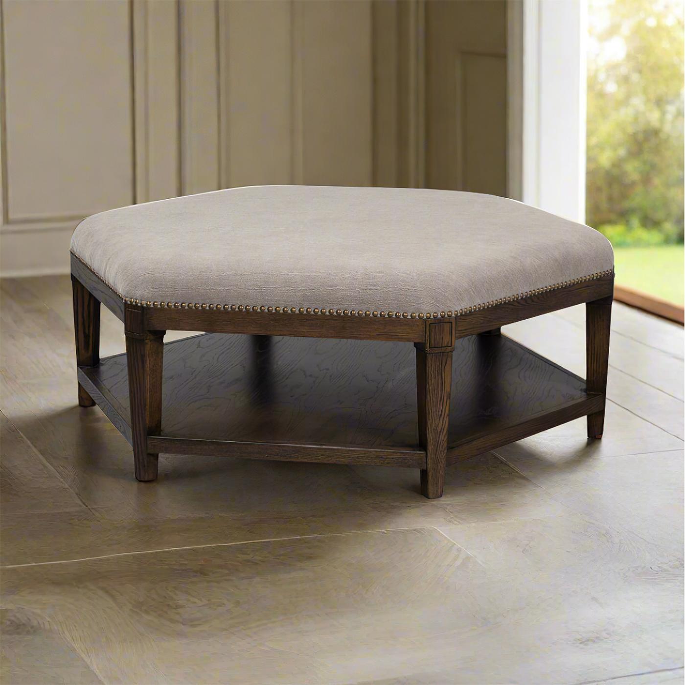 Crafted with a solid wooden frame and a rich dark finish, this ottoman is both sturdy and stylish. The plush, upholstered top provides a comfortable seating option or a chic coffee table alternative. Adorned with brass nail head trim details, it