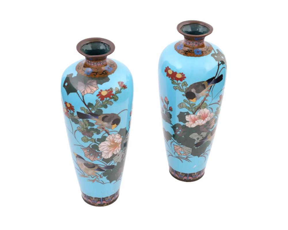 A pair of large antique Japanese copper vases with polychrome cloisonne enamel decor. Late Meiji period, before 1912. Elongated shape with pronounced neck. Birds and flowers motif against turquoise background. Floral ornaments on top and bottom.