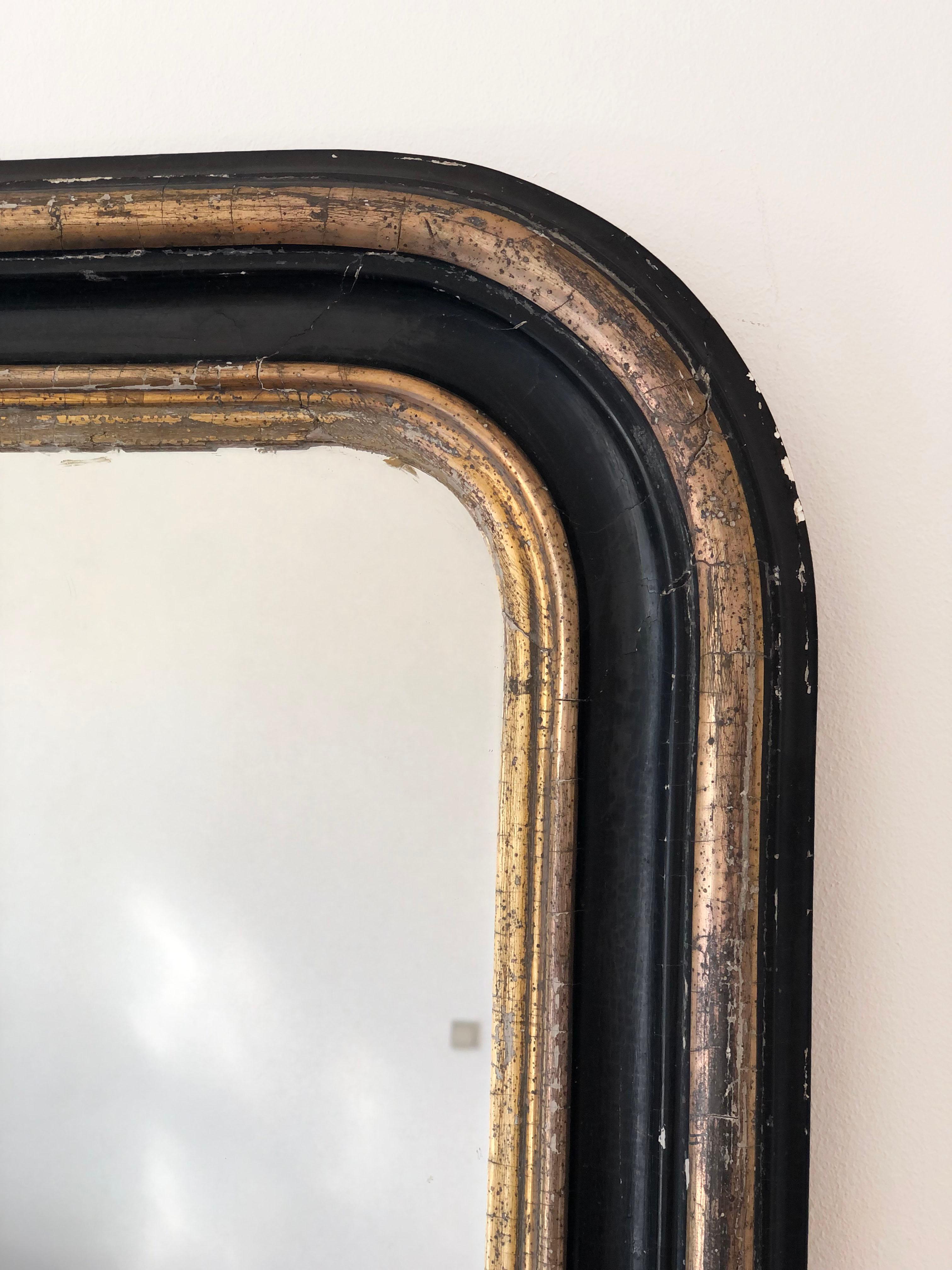 Un incantevole specchio Louis Philippe proveniente dalla Francia, risalente alla fine del XIX secolo. Lo specchio è caratterizzato da una raffinata cornice nera con finiture dorate e un piano graziosamente curvo, che emana un'eleganza e un fascino