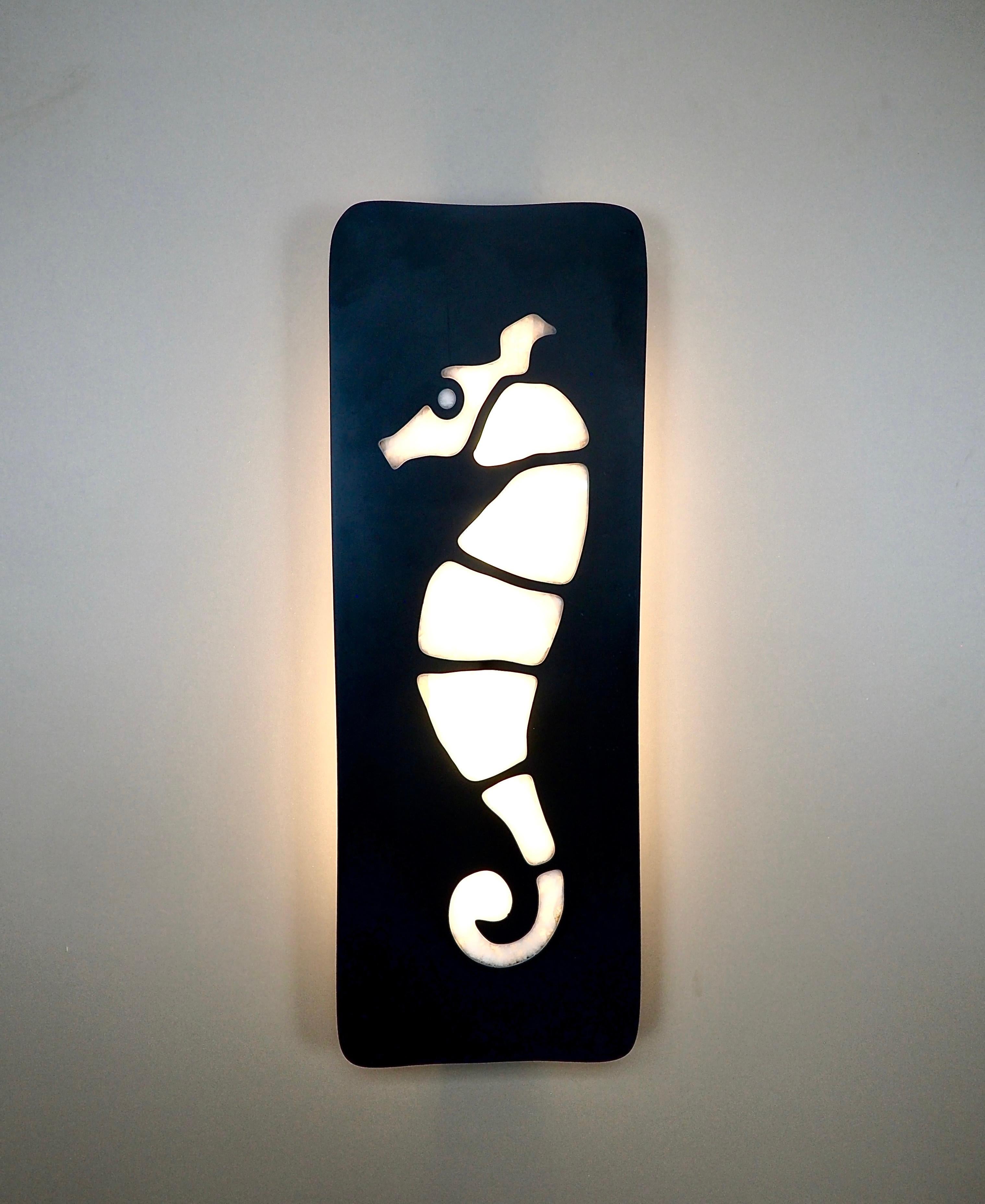 Cette grande applique est composée d'une plaque d'ardoise polie de 2 cm d'épaisseur avec une inclusion de cristal de roche en forme d'hippocampe stylisé.

L'éclairage est assuré par deux grandes ampoules E27/E26 de 30 cm protégées par un diffuseur