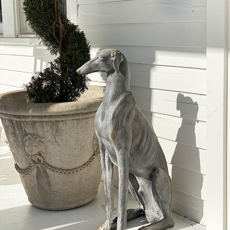 A tall gray animal statue of a whippet dog. This piece will be fabulous styled by a front door, on a patio, or by a fireplace. (See our photos for inspiration) Created with fiberglass, this tall dog statue will bring a touch of classicism to any