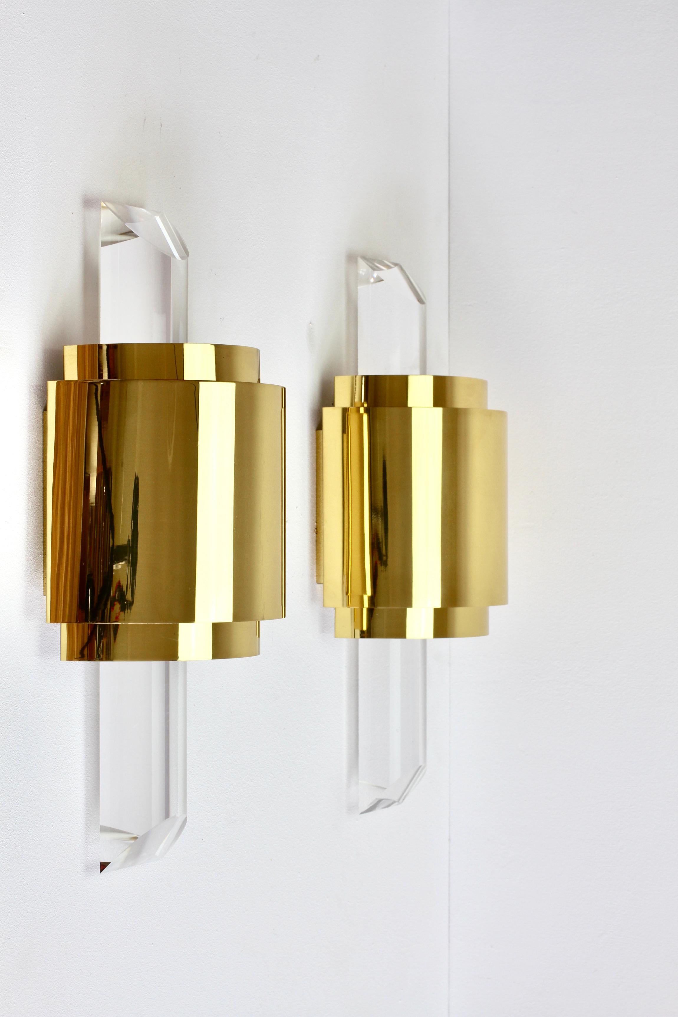 Hollywood Regency style pair of large, oversized pair of cut / angled acrylic / lucite wall-mounted lamps, lights or sconces in the style of Karl Springer and made in the latter part of the mid 20th century circa 1975 -1985. These illuminate