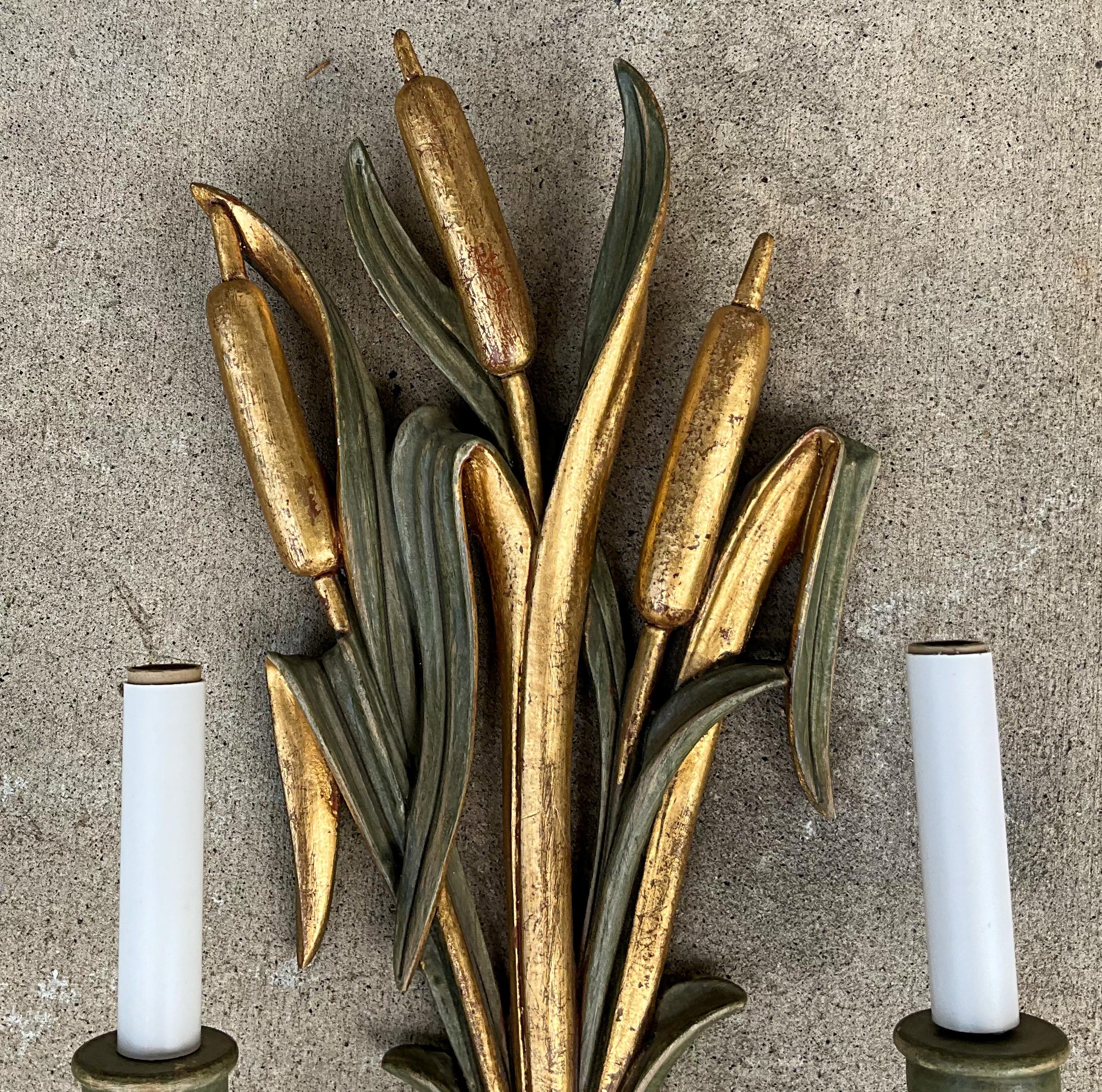 This is a lovely pair of large scale Hollywood Regency carved parcel gilt Italian sconces depicting cattails, leaves and floral motifs. They are marked and in working order.