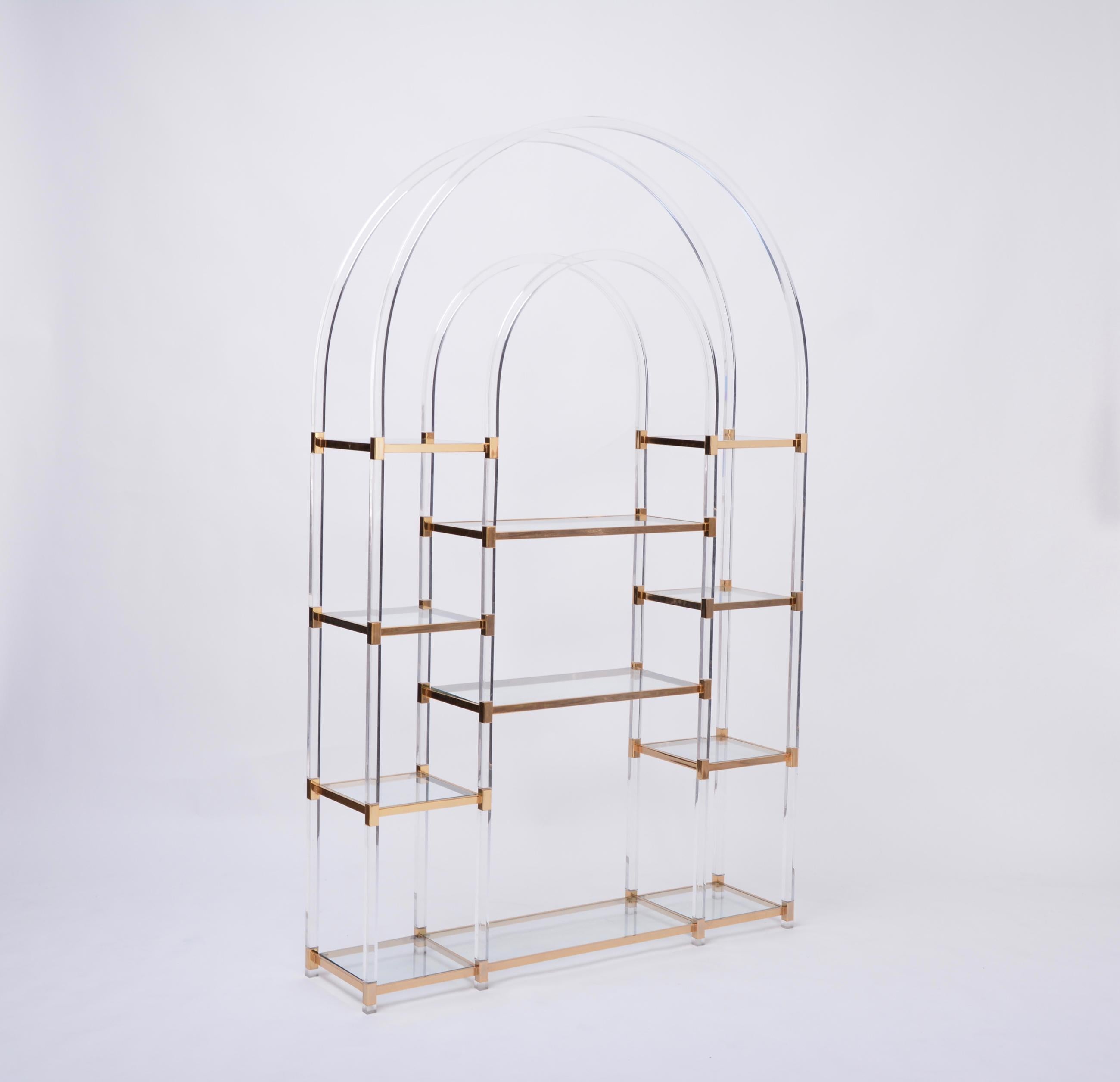 Large Hollywood Regency style shelving unit by Maison Jansen
Spectacular design from Maison Jansen. The shelving unit consist of transparent plexi glass formed rods, crowned by a plexi glass arch. The rods and archs are joint by brass joins. The