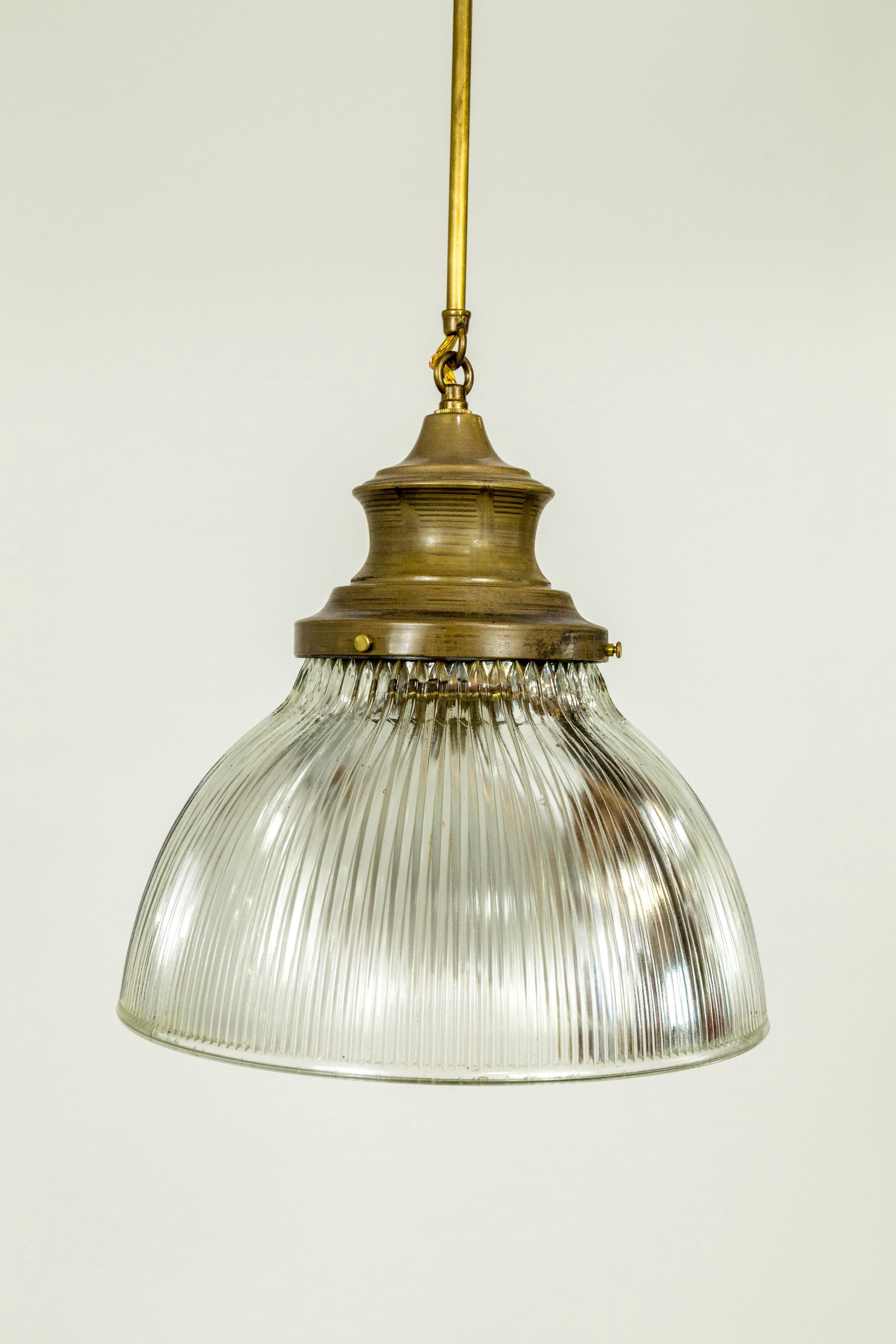 Large, thick, holophane glass pieces from the early 20th century, newly fashioned into pendant lights with brass glass holders, stem, and canopy. 12.25