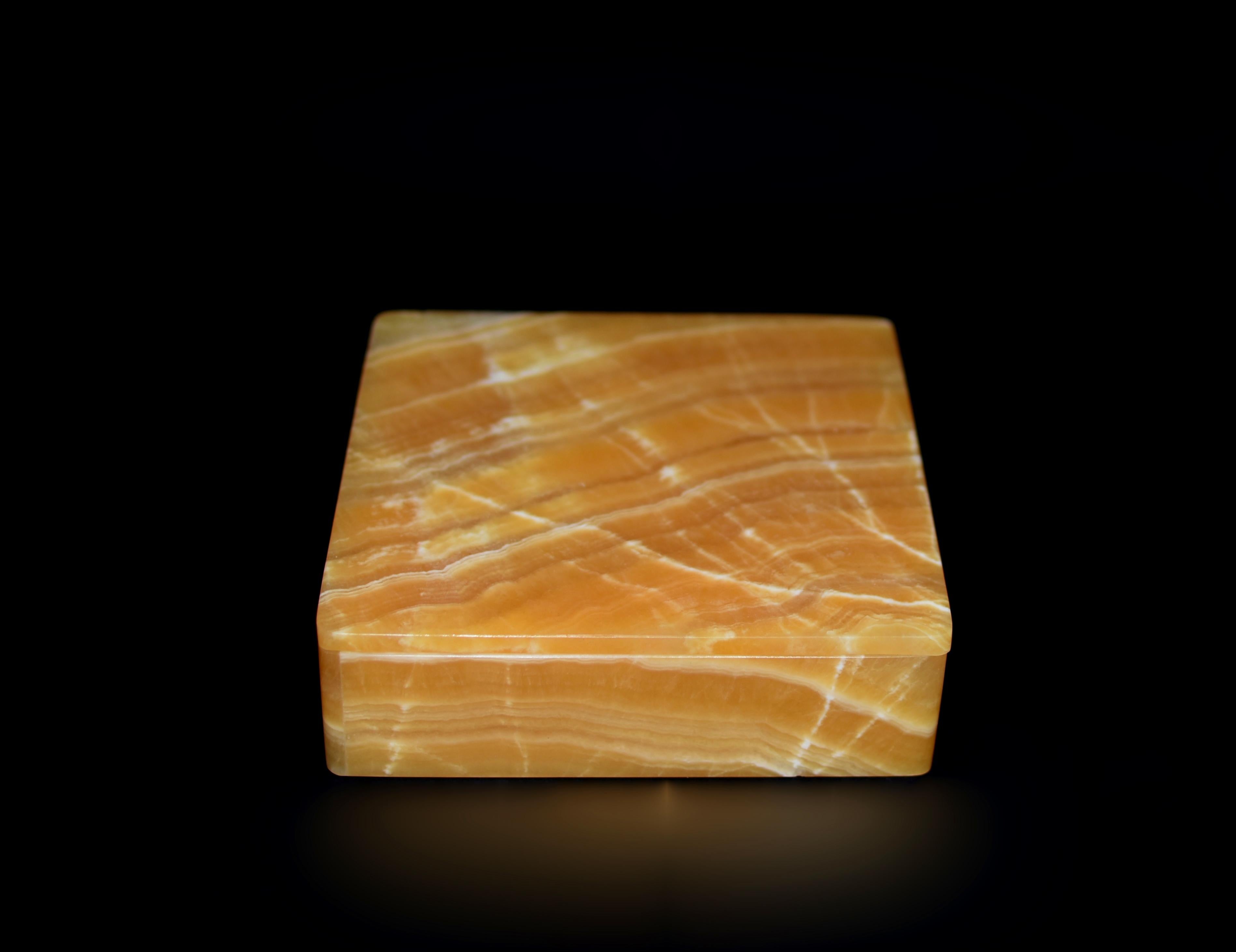 This exquisite creation is crafted from the finest rare honey calcite onyx sourced from Pakistan, using only single boards (full one piece slab) of stones for all sides of the box. Hand made by a master artisan in Italy, showcasing beautiful