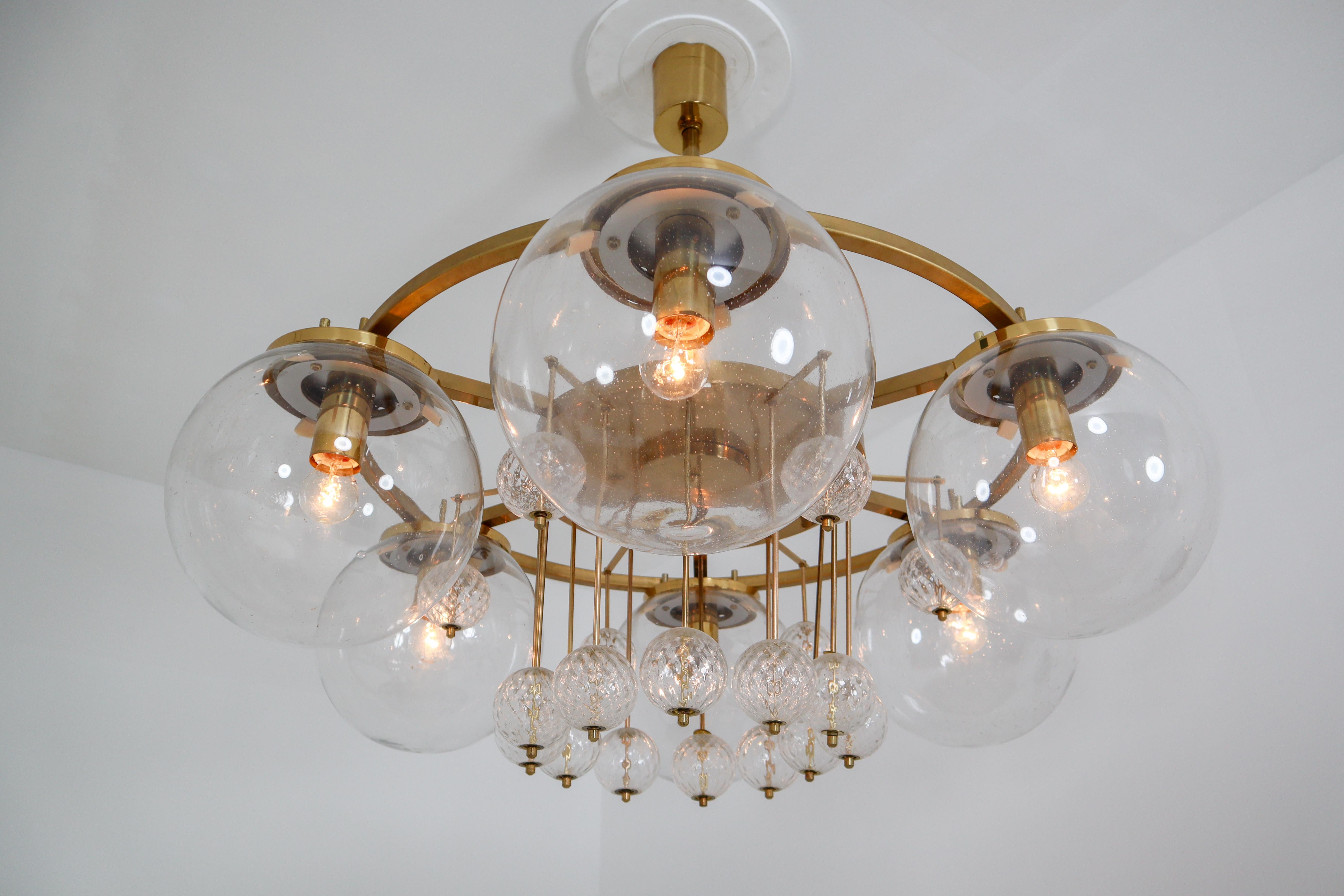 Large hotel chandelier with brass fixture and large hand blowed glass. The chandelier with brass frame consist of six lights, formed in a circle, with glass shades. The pleasant light it spreads is very atmospheric. Completed with the structured
