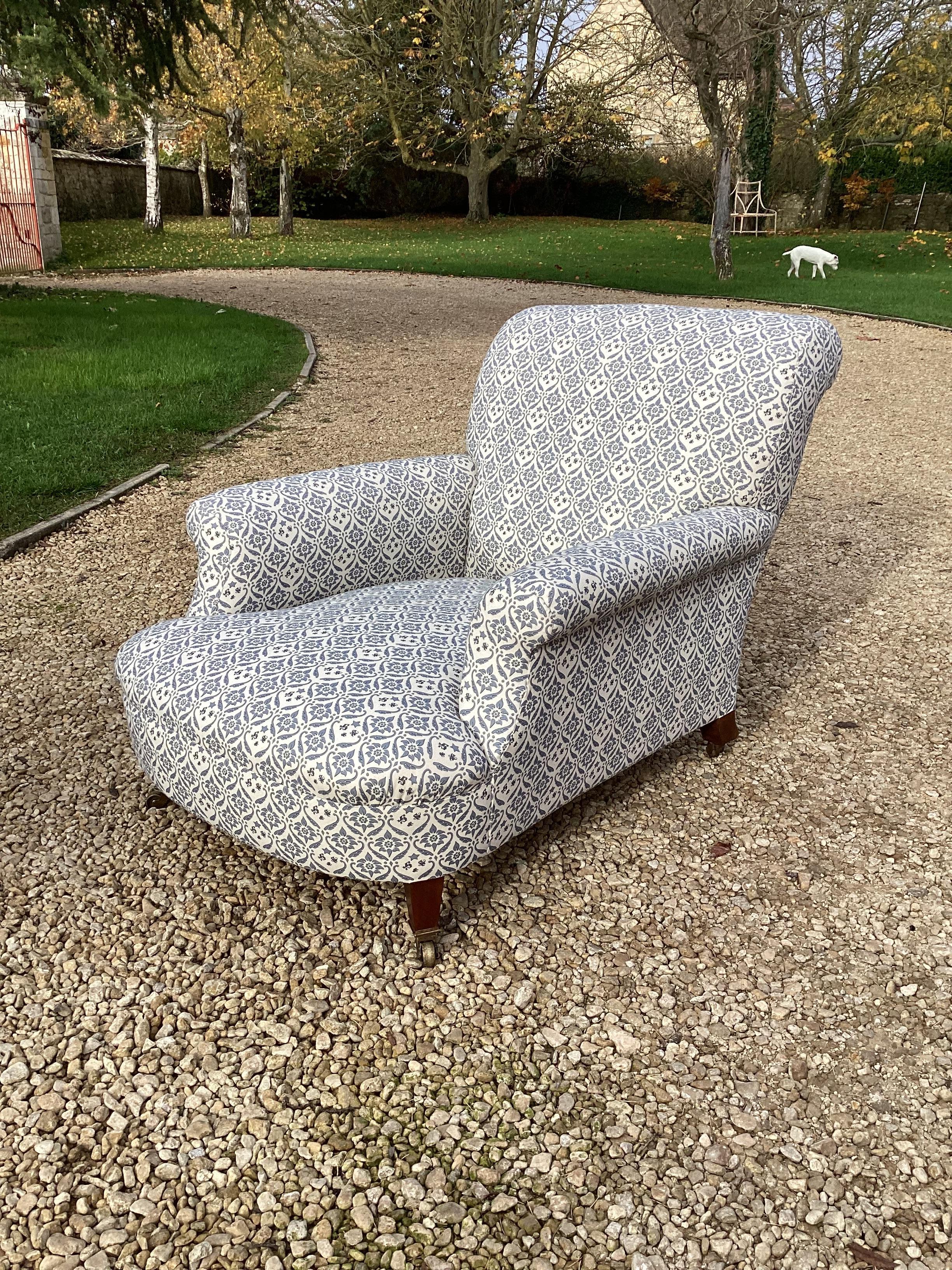 A large and deep seated Howard & Sons club armchair, with strong frame and raised on square tapering legs and original brass castors, stamped Howard & Sons to all four castors and rear inside leg with inventory number, newly upholstered in blue