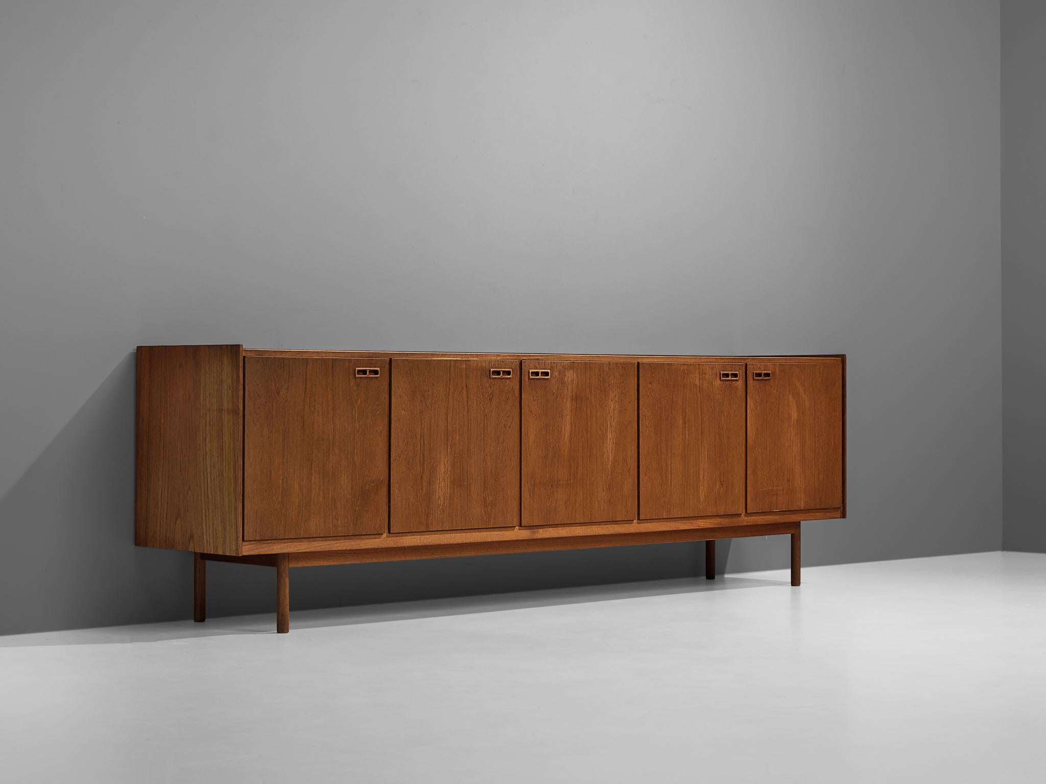 Ib Kofod-Larsen, sideboard, teak, fabric, Denmark, 1950s.

This Danish sideboard in teak features the wonderful Scandinavian Modern aesthetic of the 1950s. The minimalist design focuses on the geometric handles and the expression of the wood. The