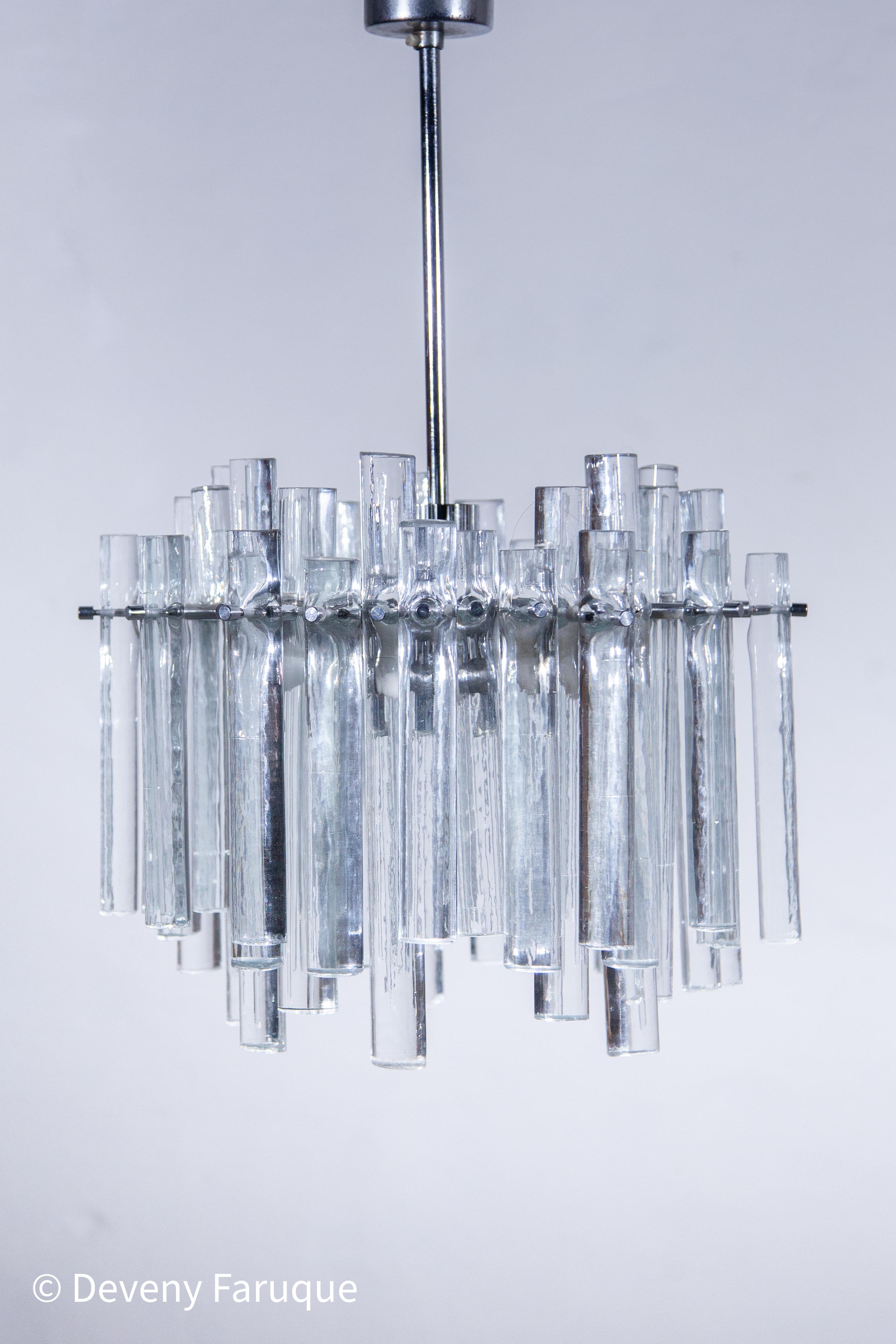 Lampadario in vetro artistico con bacchette in vetro fuso di varie lunghezze con texture ghiacciata. La cornice è nella sua finitura cromata originale. Firmato dal creatore Kinkeldey. Una lampada davvero eccezionale. L'azienda è nota soprattutto per