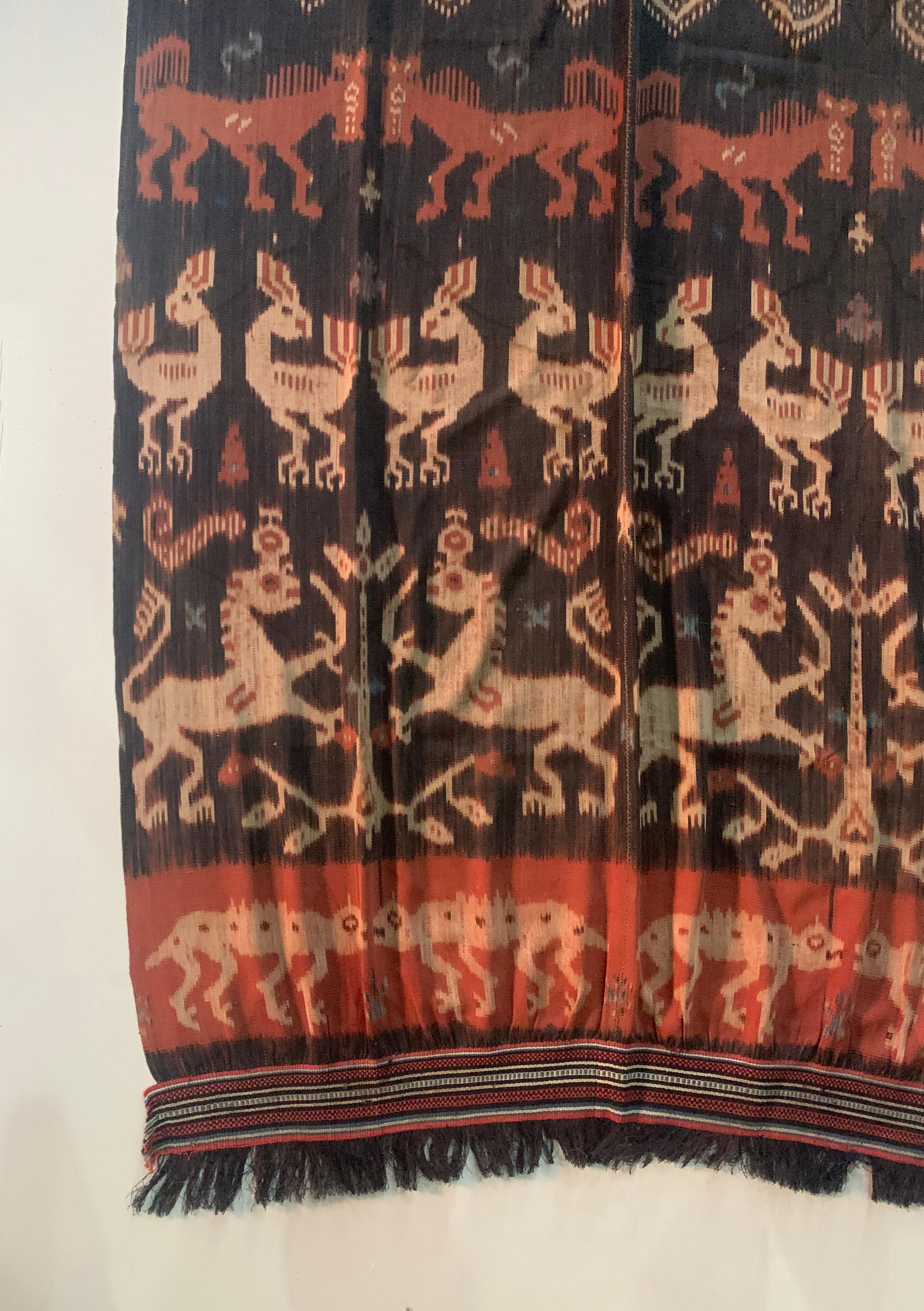This Ikat textile originates from the Island of Sumba, Indonesia. It is hand-woven using naturally dyed yarns via a method passed on through generations. It features a stunning array of distinct tribal patterns as well as chicken, horse, and reptile