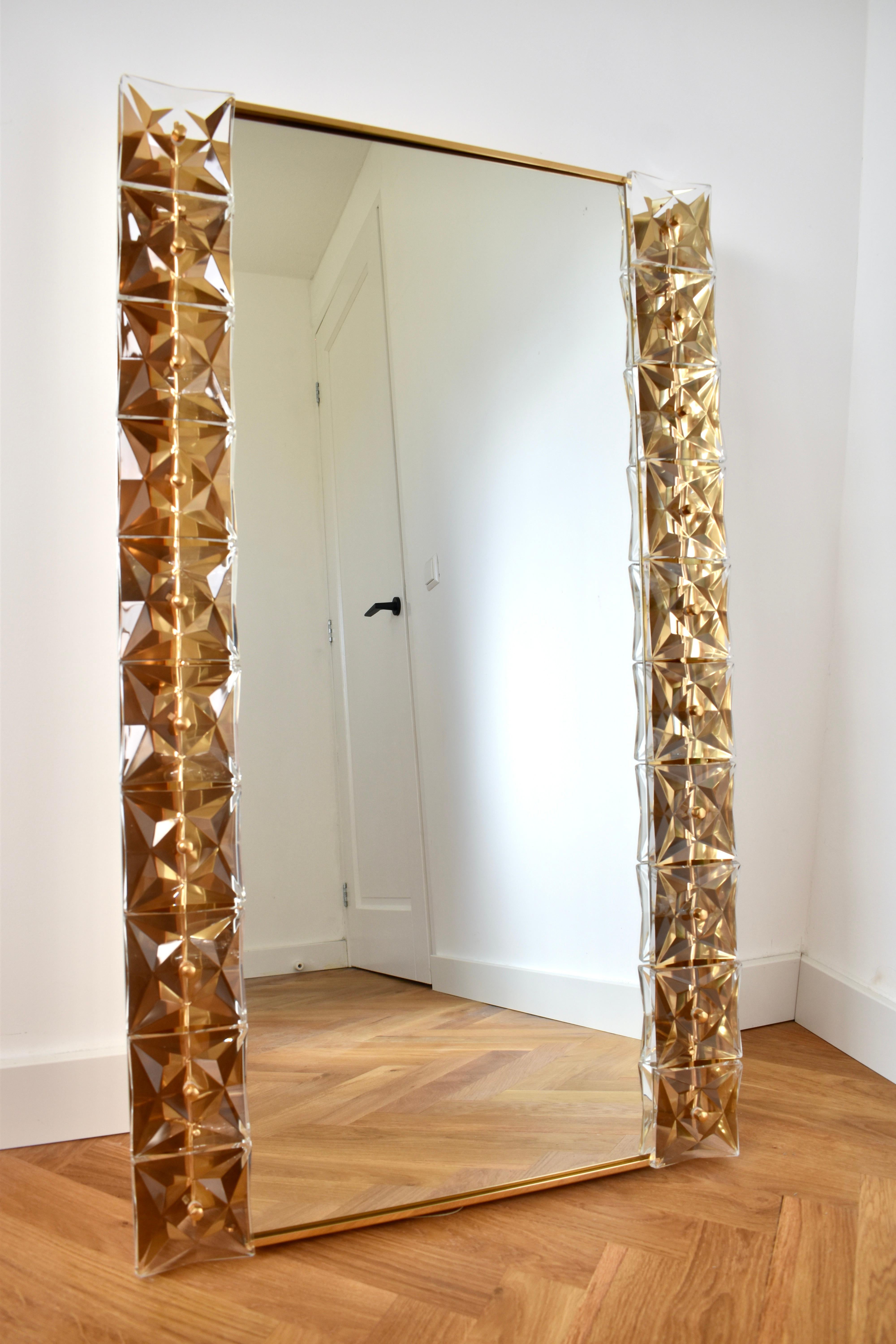 An extraordinary illuminated crystal mirror by the German lighting manufacturer Kinkeldey, dating back to the 1970s. The gilded brass frame with faceted crystal elements reflects the integrated lighting beautifully, casting a warm and elegant glow.