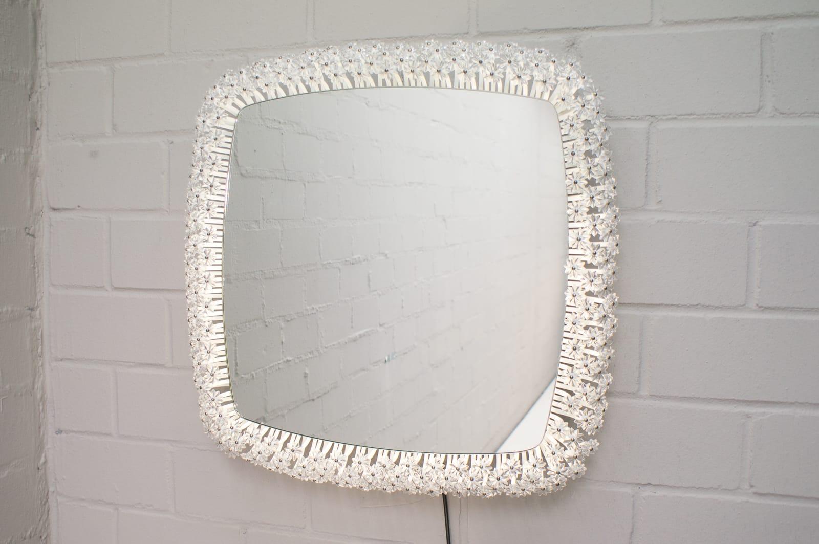 Modernist wall mirror with illuminated background. 
Surrounded by crystal glass blossoms. 
Designed in the 1950s and produced in the 1960s.
Design by Emil Stejnar for Rupert Nikoll Austria, 1950s.
Original mirror in metal frame with three rows