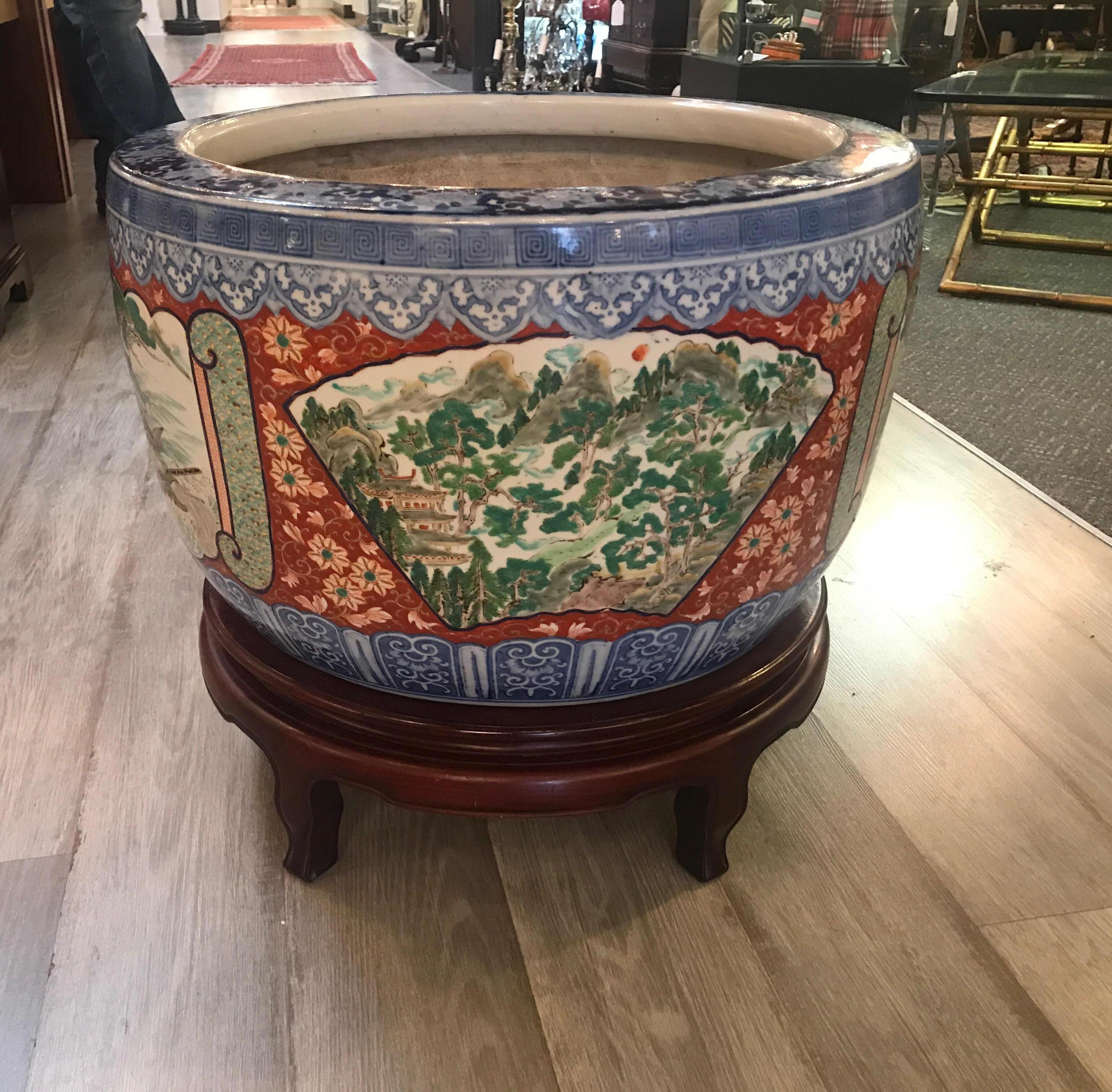 Large Japanese porcelain jardinière from the Meiji period. The hand painted porcelain with 4 scenic panels of equestrian and samurai decorated cartouches. Comes with a later Chinese hardwood stand.
  