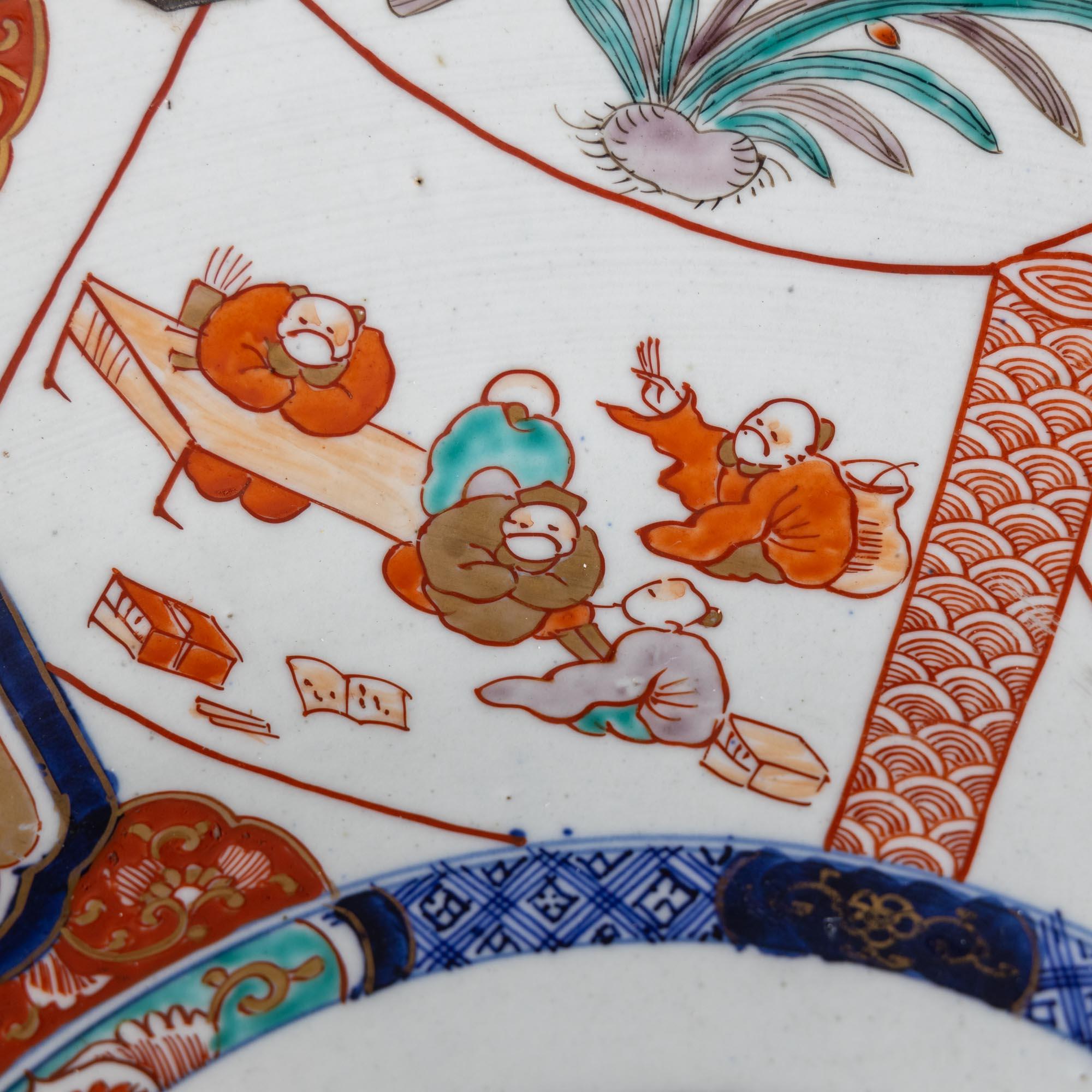 Großer Imari-Porzellanteller mit weißem Grund und rot-blauem Dekor. Die Platte ist mit einer Wandhalterung ausgestattet.