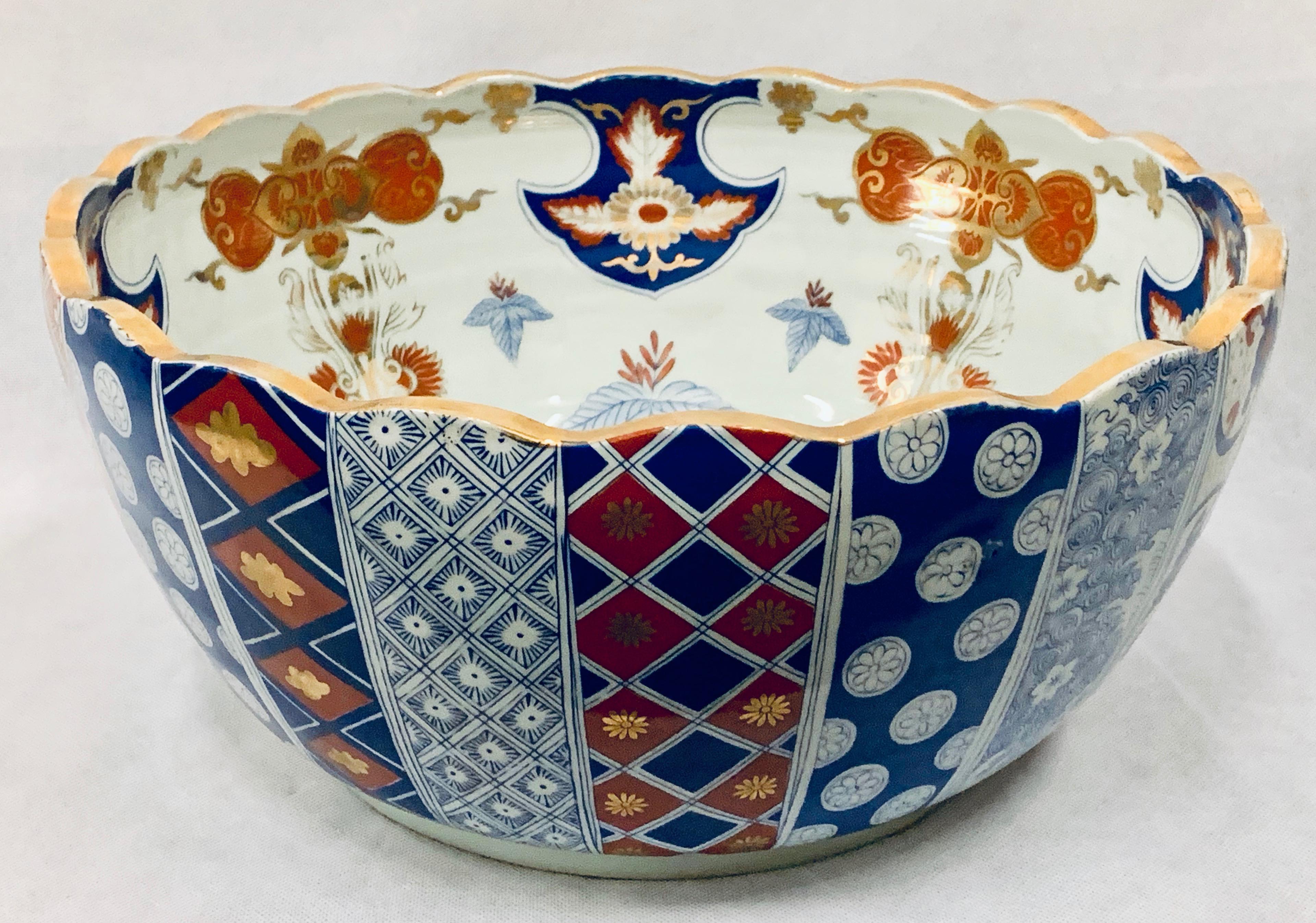 Large Meiji period porcelain Imari punchbowl. The interior has a charming mountainous scene with a house, pagoda, pine tree and waterfall all in underglaze blue. The surrounding area is filled with fish scale pattern and various leaves in iron red,