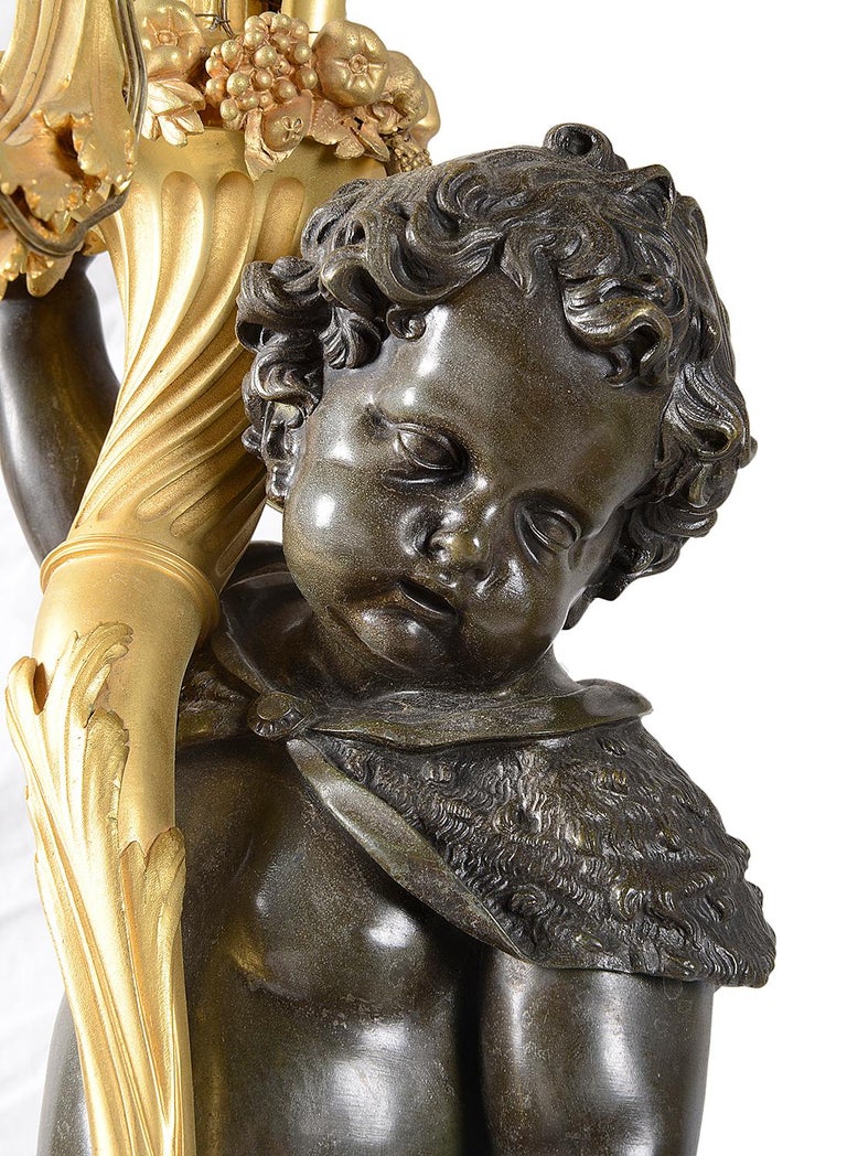 A large and important fine quality pair of 19th century gilded ormolu and bronze candelabra, each with scrolling foliate six branch sconces, supported by cornucopia held by a pair of semi clad opposing putti. Raised on gilded ormolu egg and dart
