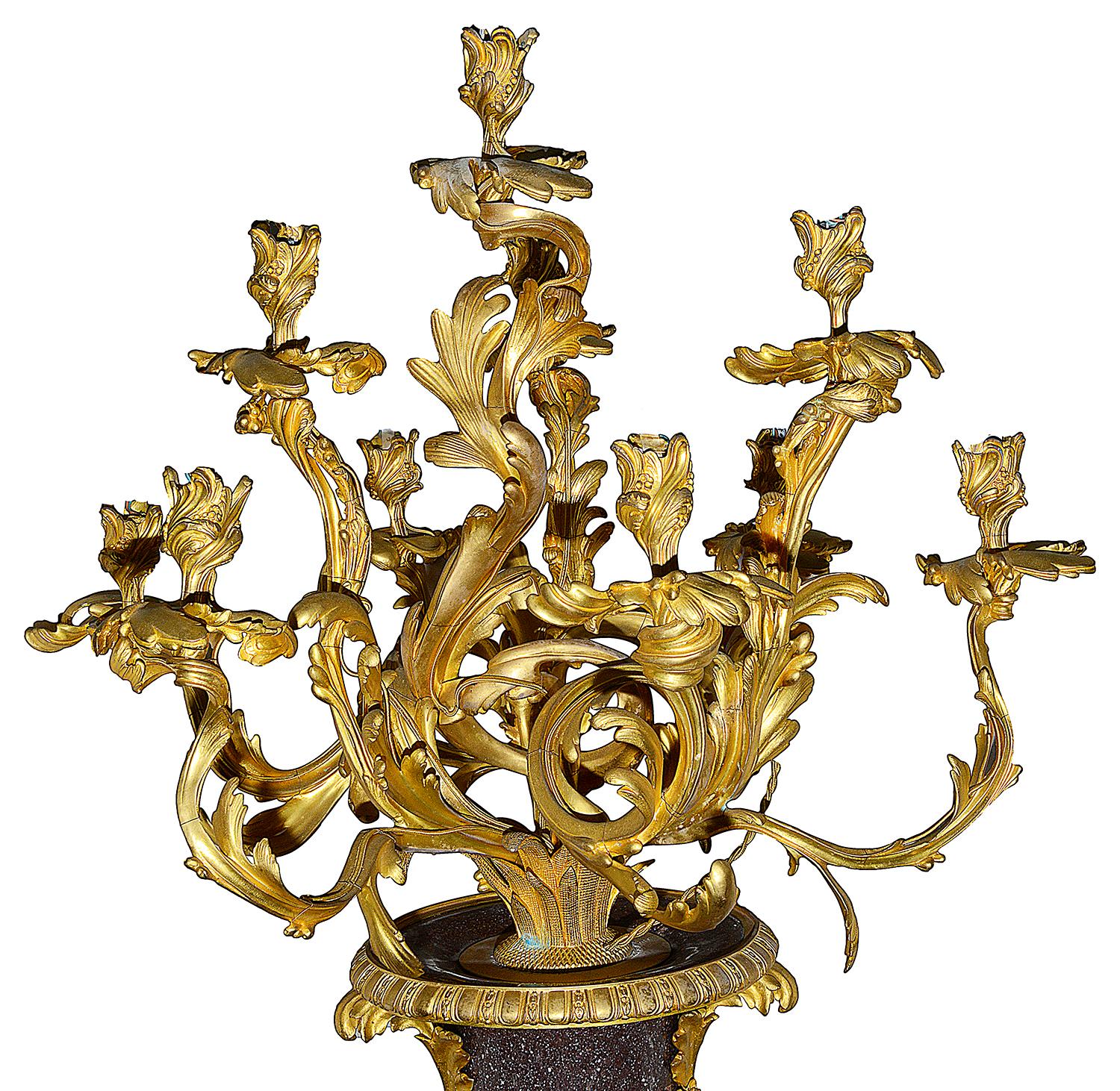 A wonderful quality pair of late 19th century Rococo influenced gilded ormolu scrolling ten branch candelabra, mounted on twisted, reeded Porphyry urns, raised on waisted socles with beeded square ormolu plinths. Measures: 154cm(61