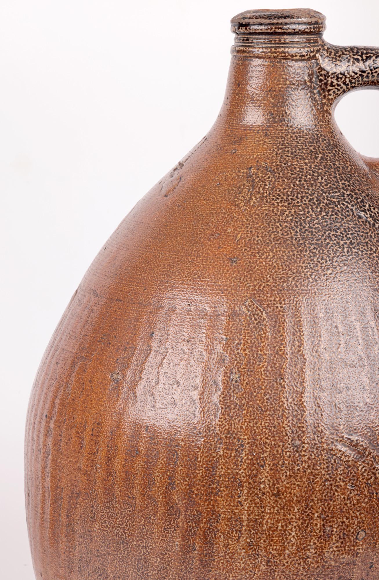 A large and highly impressive antique salt glazed Bellarmine dating from the 17th or early 18th century.  The stoneware Bellarmine stands on a narrow flat round base with a tall round bulbous body with a narrow neck and ring top with a small thick