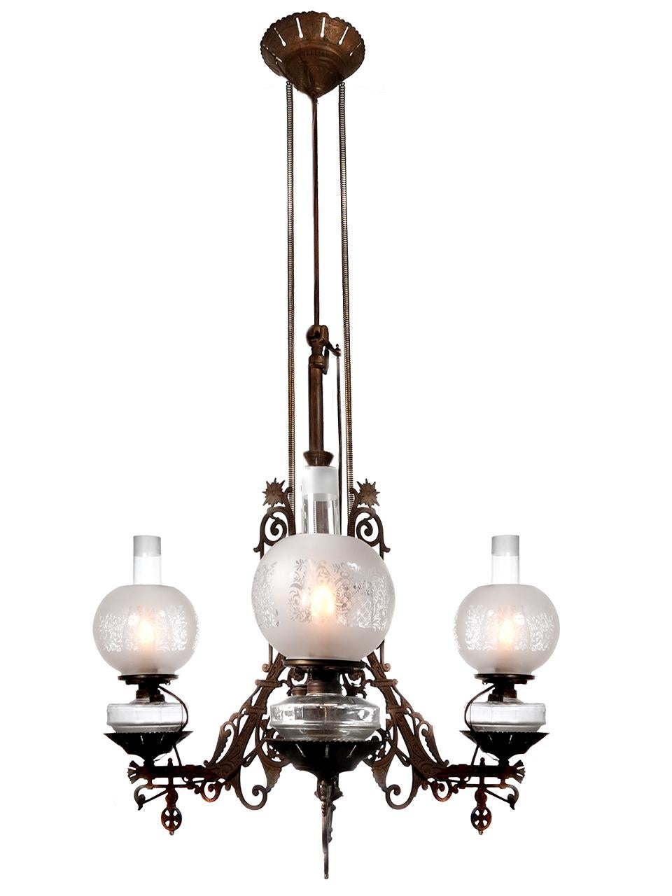 Se trata de un bonito candelabro original de 3 fuentes de queroseno con una ornamentada estructura de hierro fundido. El cristal es perfecto y todo él con bonitos globos grabados y esmerilados. Ahora está preparada para tres bombillas E26. La