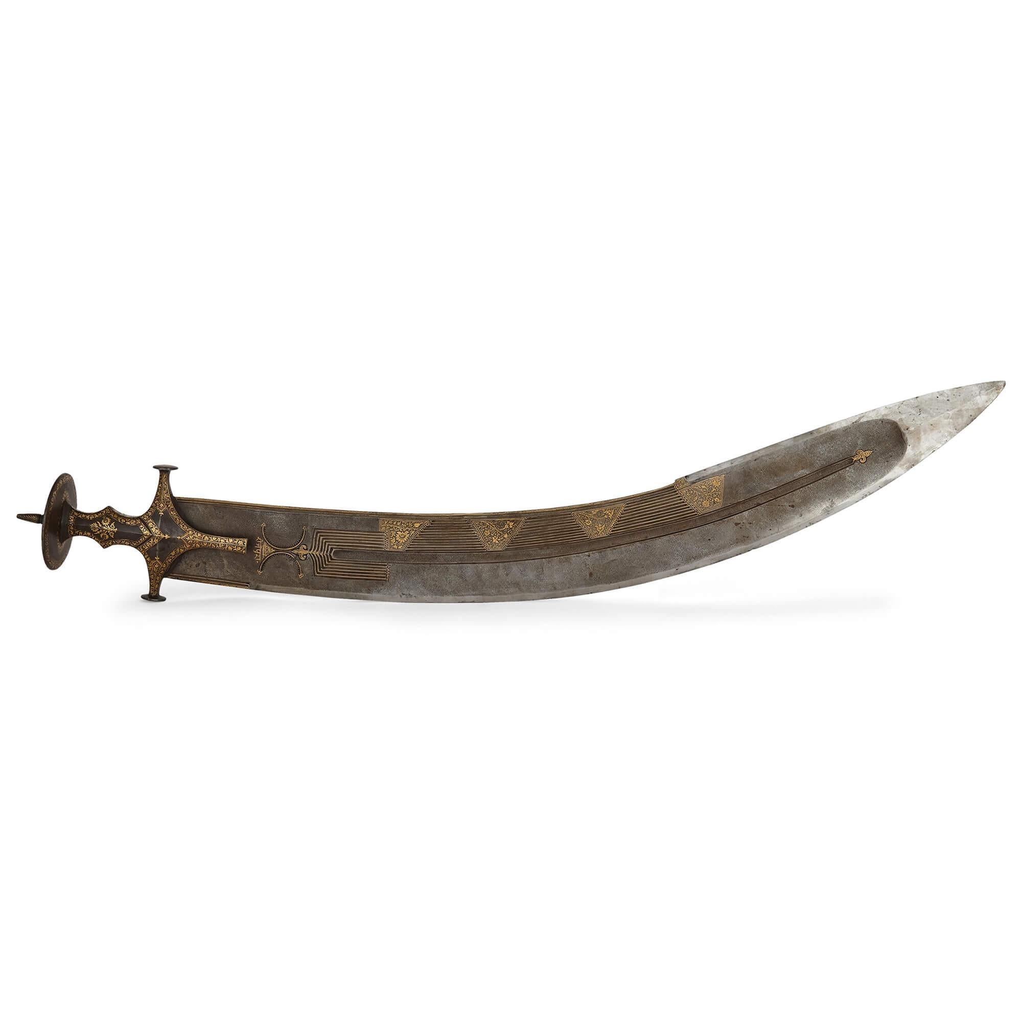 Large Indian gold damascened steel tegha sword.
Indian, c. 1850
Length 112cm, width 16cm, depth 10cm

This remarkable sword is a tegha, a large Indian sword designed to be used in a ceremonial manner. The curved blade of the sword features a