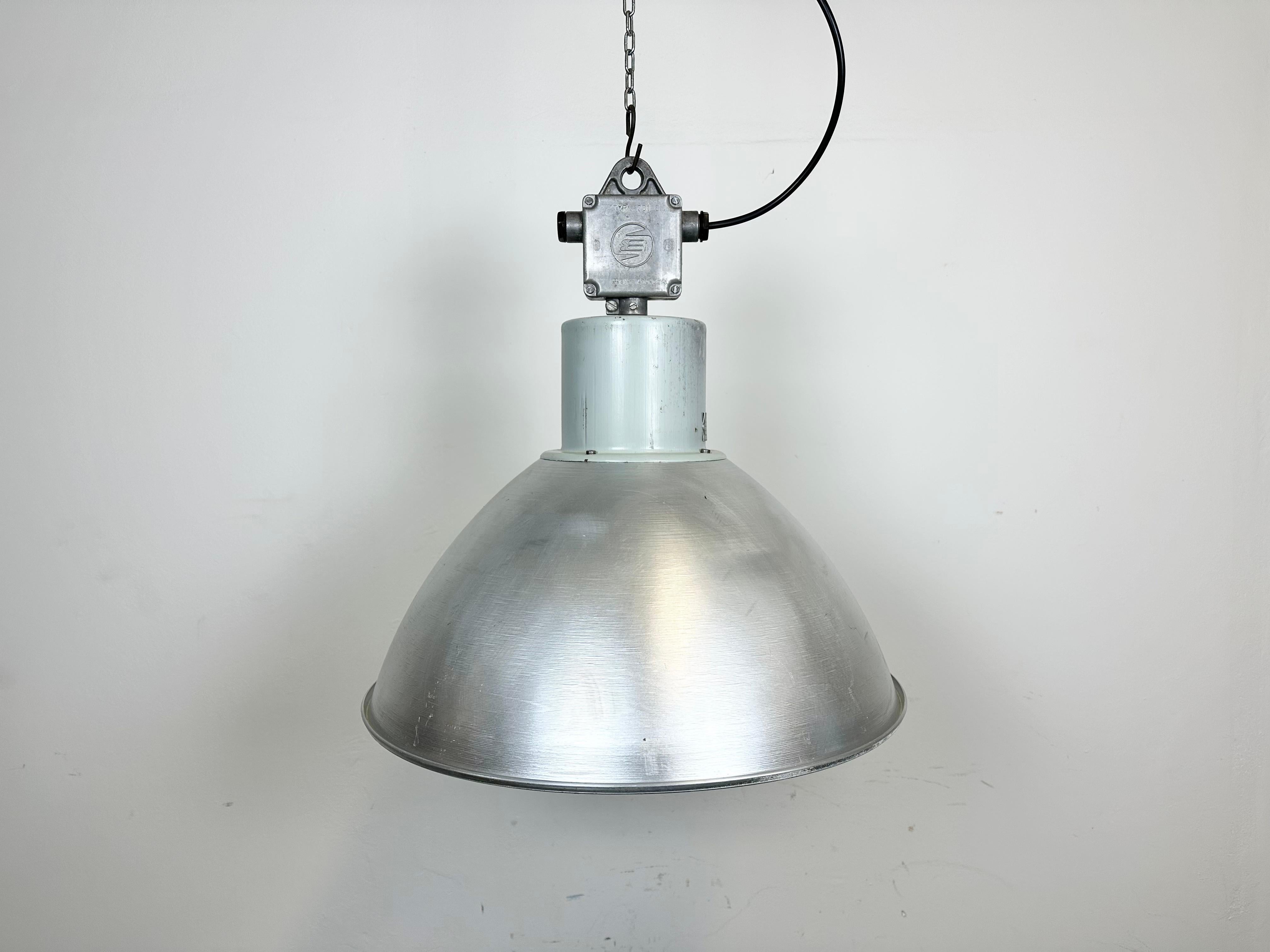 This pendant lamp was made by Elektrosvit and originally used in a factory in former Czechoslovakia in the 1960s. The piece is comprised of an aluminum lampshade and an iron top with cast aluminum box. The lamp is fully functional and features a new