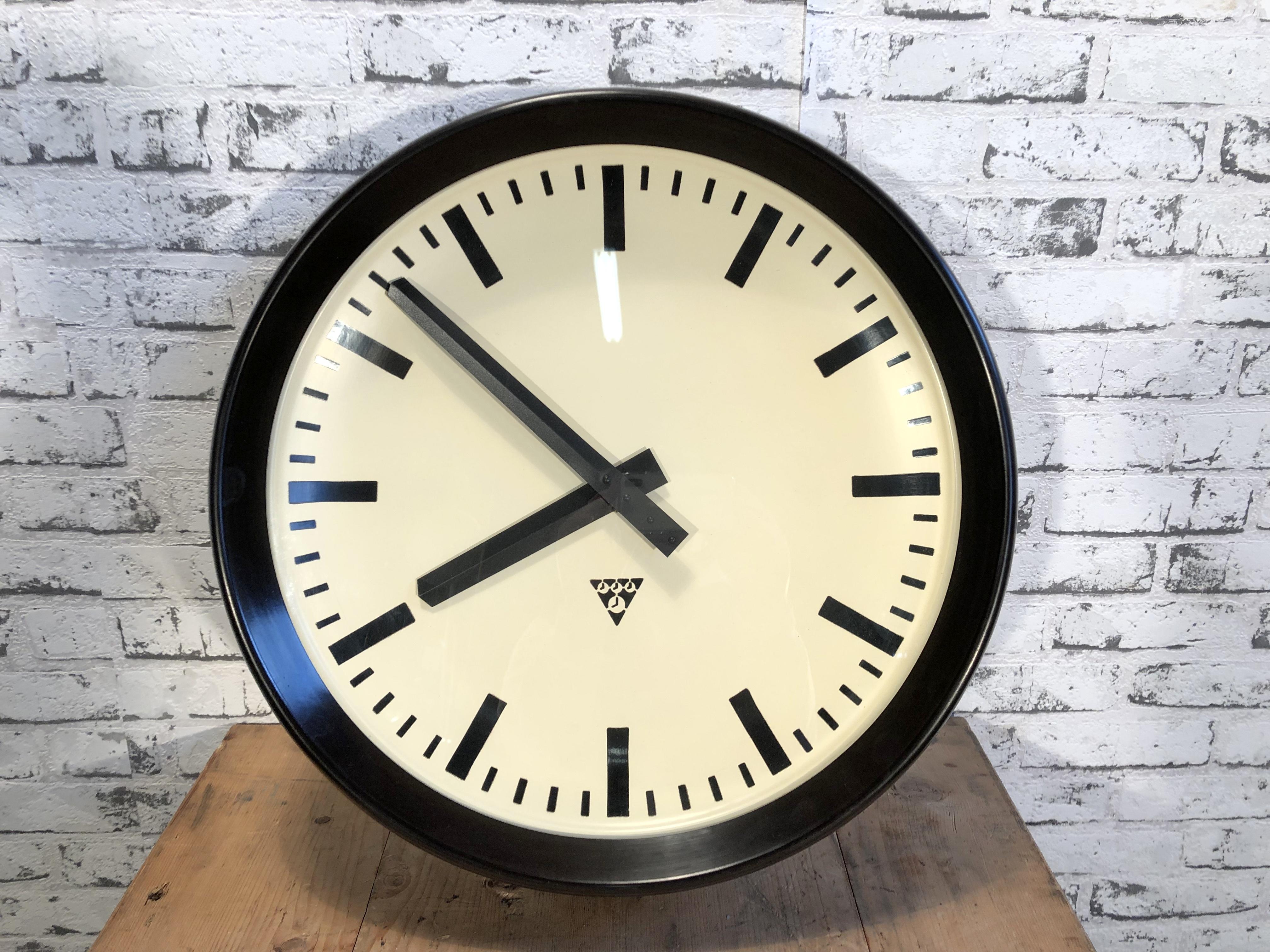 This large wall clock was produced by Pragotron in former Czechoslovakia during the 1960s.It features a brown bakelite frame, aluminum dial and clear glass cover. The piece has been converted into a battery-powered clockwork and requires only one