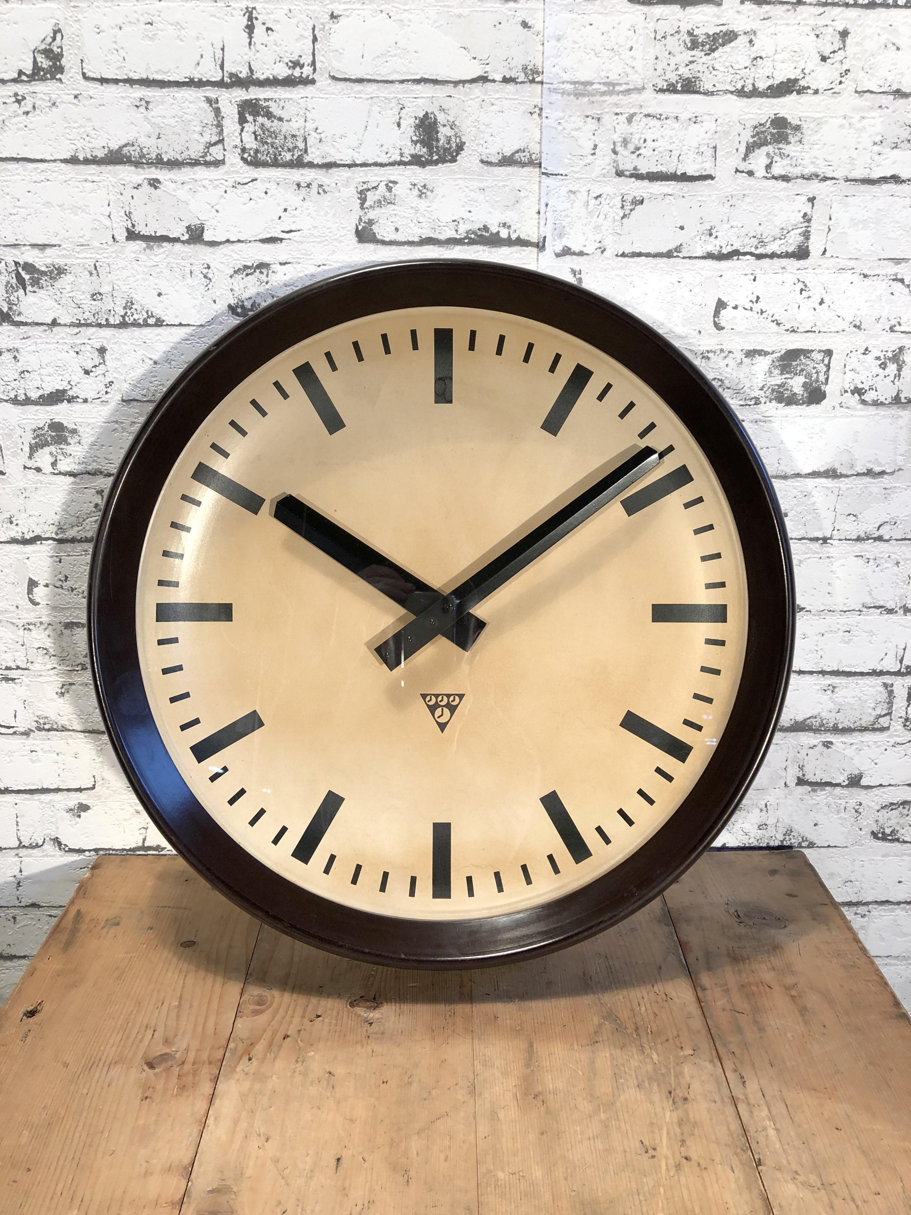 This large wall clock was produced by Pragotron in former Czechoslovakia during the 1960s.It features a brown bakelite frame, aluminium dial and clear glass cover.The piece has been converted into a battery-powered clockwork and requires only one