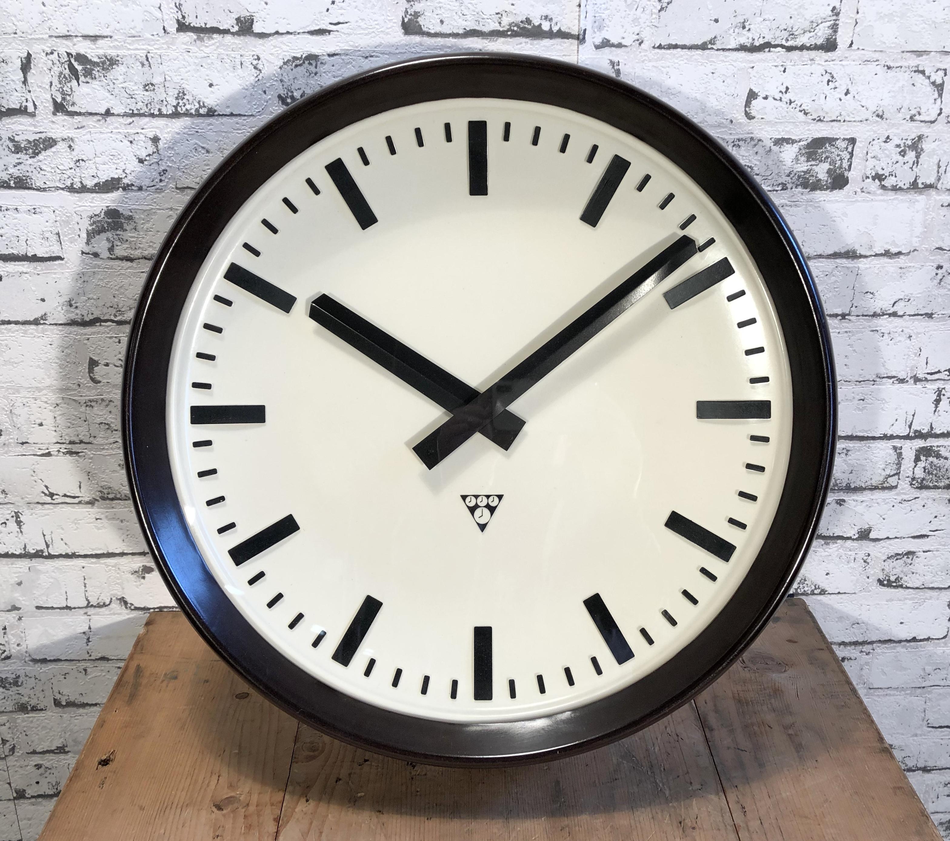 This large wall clock was produced by Pragotron in former Czechoslovakia during the 1960s.It features a brown bakelite frame, white plastic dial, aluminium hands and clear glass cover. The piece has been converted into a battery-powered clockwork
