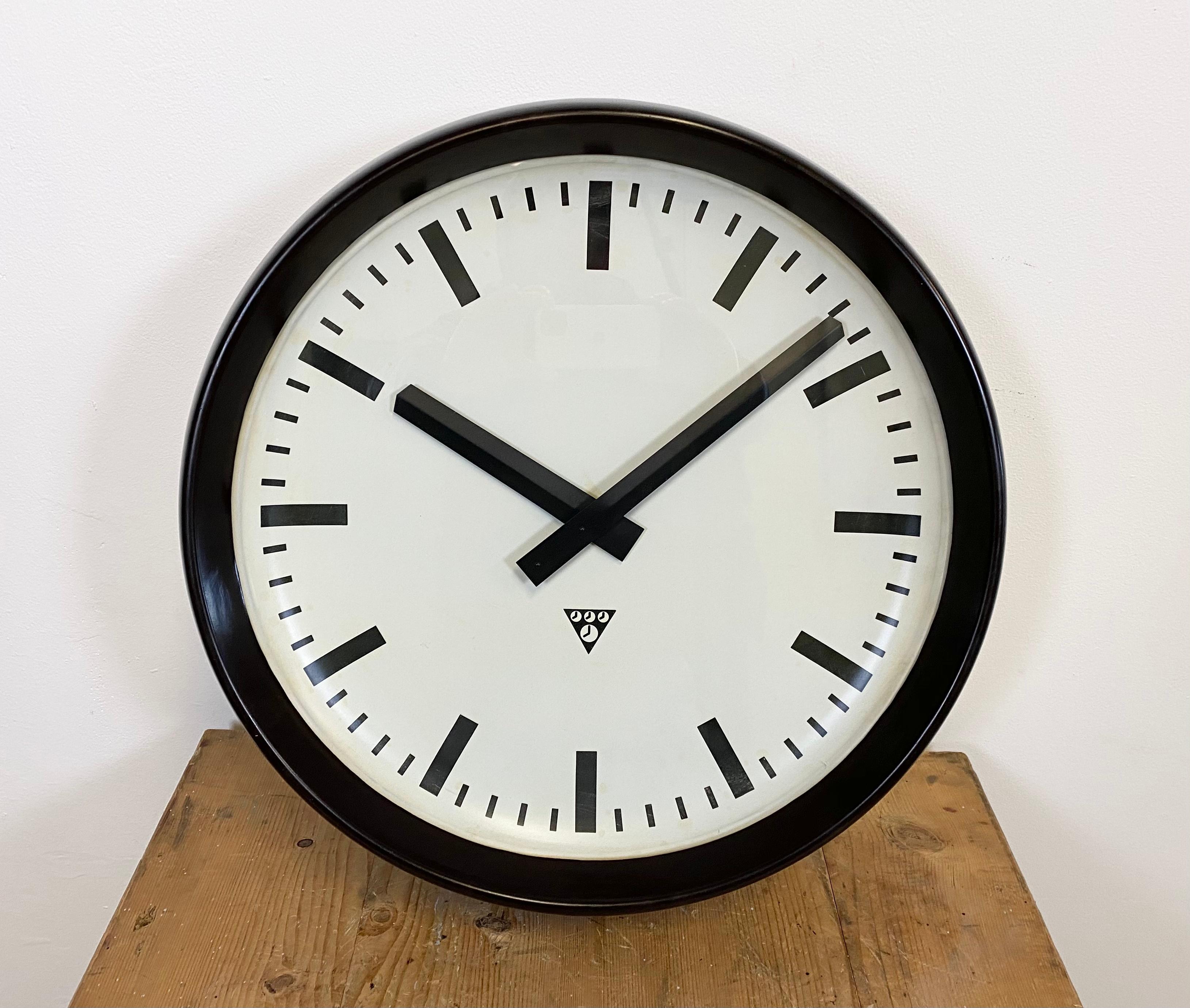 This large wall clock was produced by Pragotron in former Czechoslovakia during the 1960s. It features a brown Bakelite frame, an aluminum dial, an aluminum hands and a clear glass cover. The piece has been converted into a battery-powered clockwork