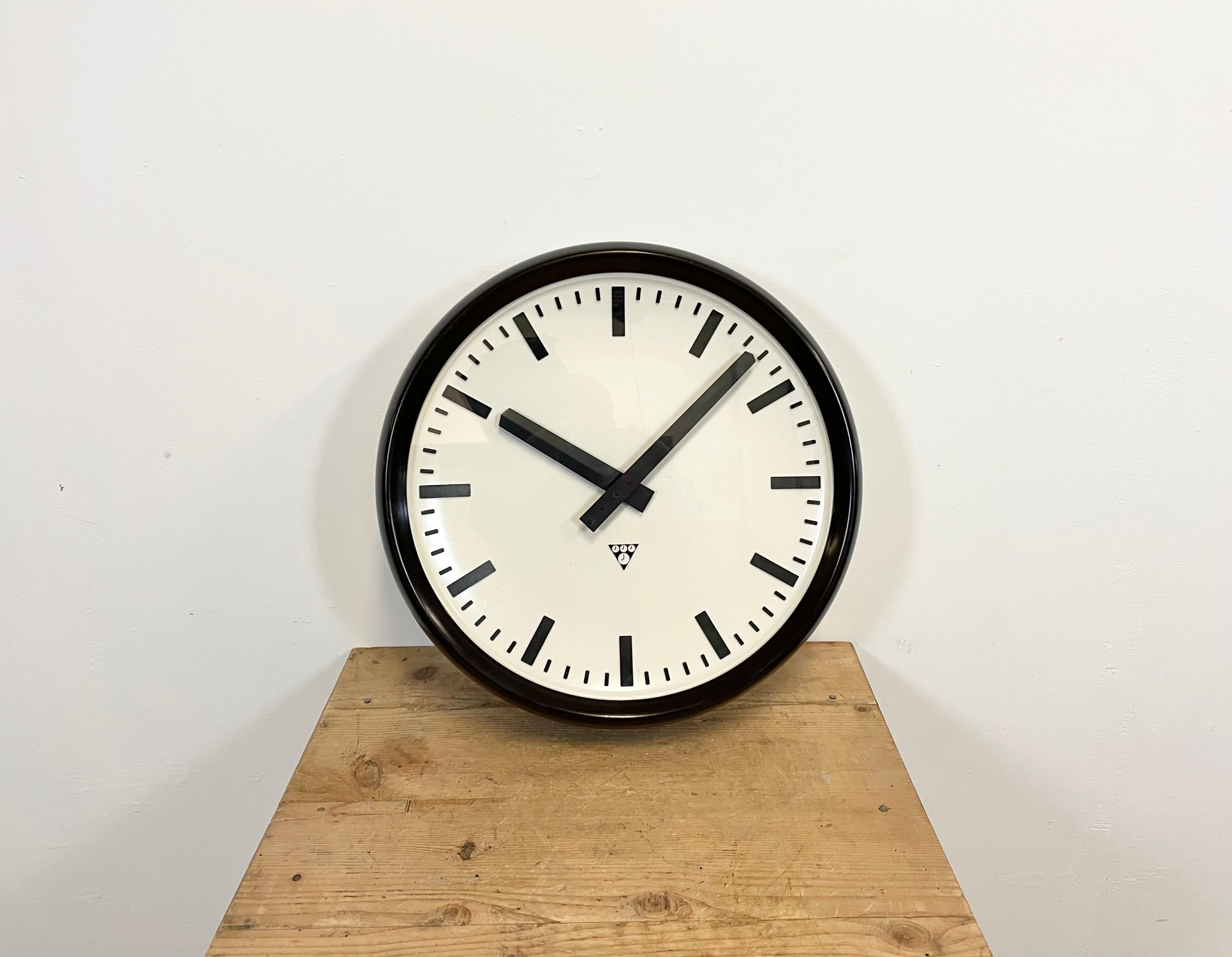 This large wall clock was produced by Pragotron in former Czechoslovakia during the 1960s. It features a brown Bakelite frame, a white Bakelite dial, an aluminium hands and a clear glass cover. The piece has been converted into a battery-powered